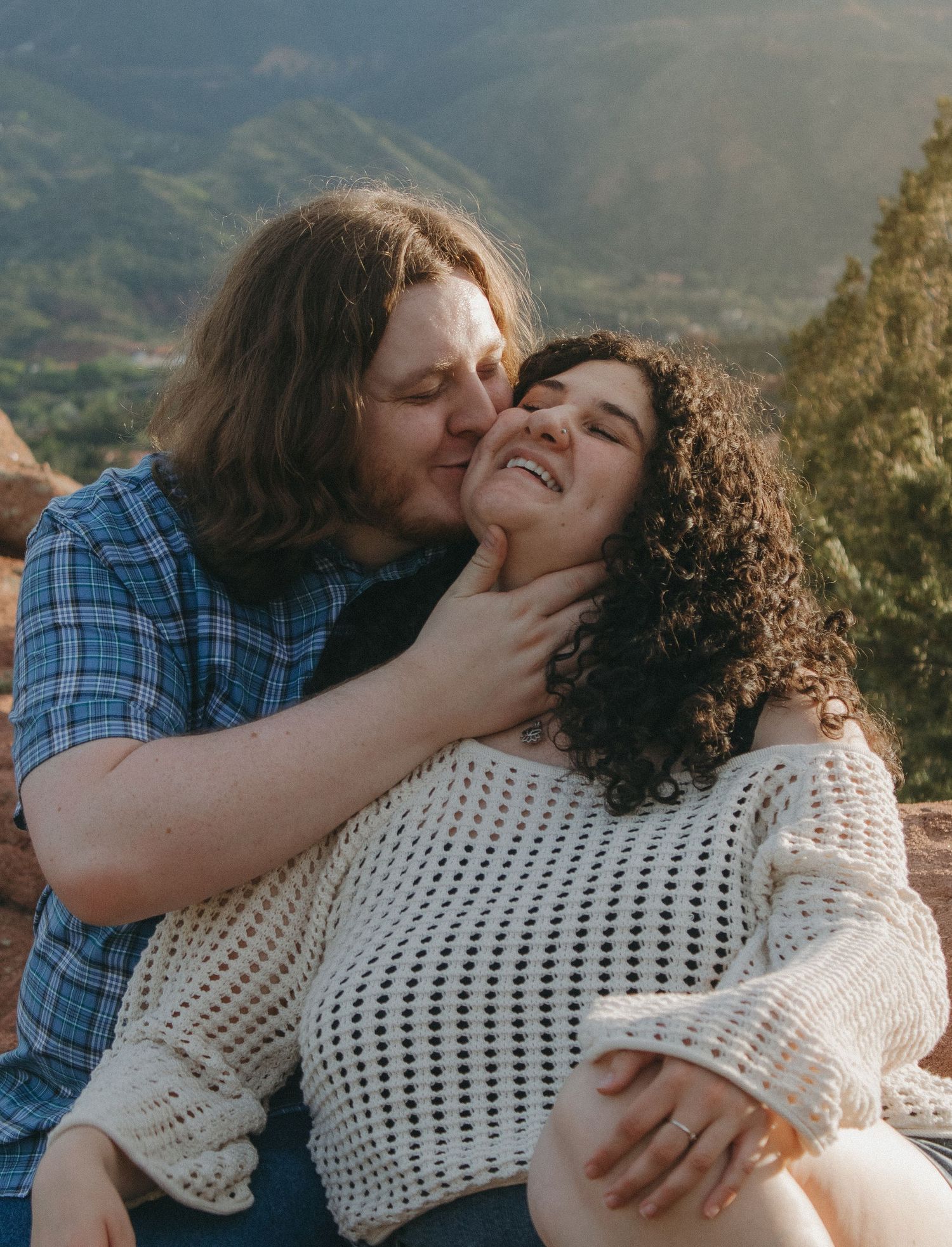 A tender moment between a couple against a mountainous backdrop.