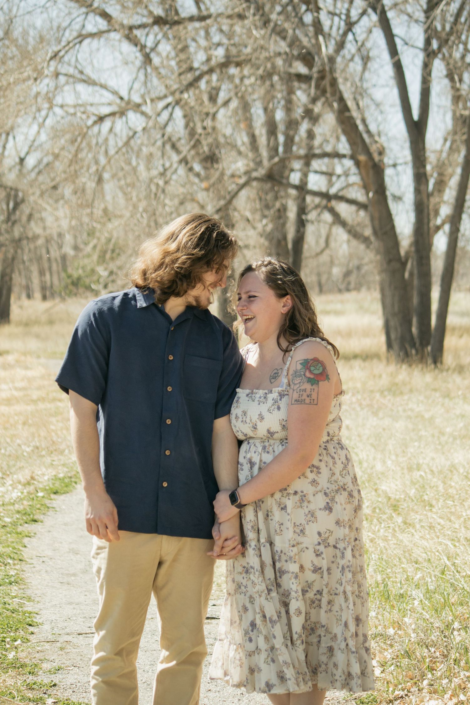 A couple sharing a laugh while walking along a tree-lined path.