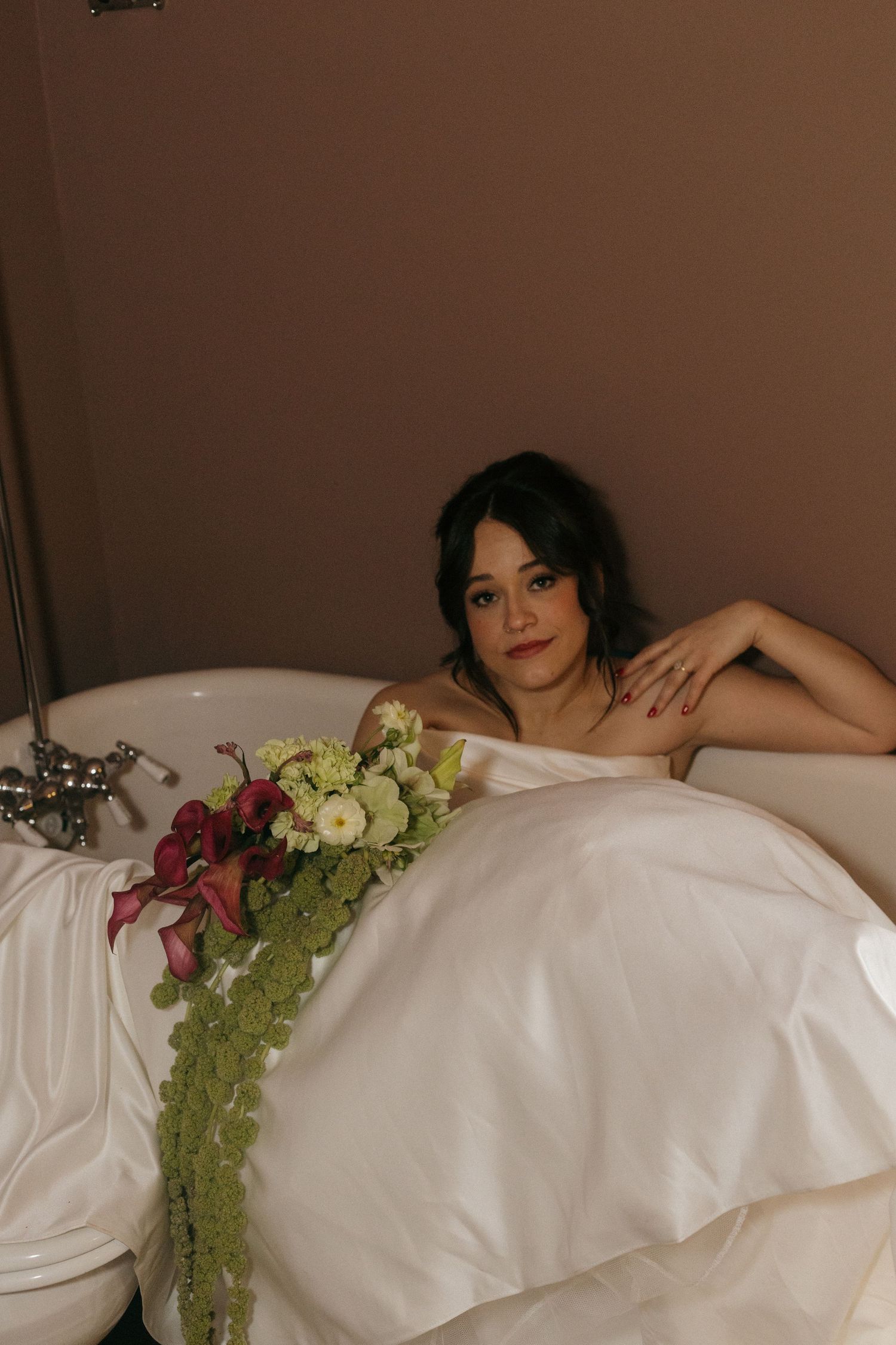 Artistic bridal portrait with flowers against white bedding.