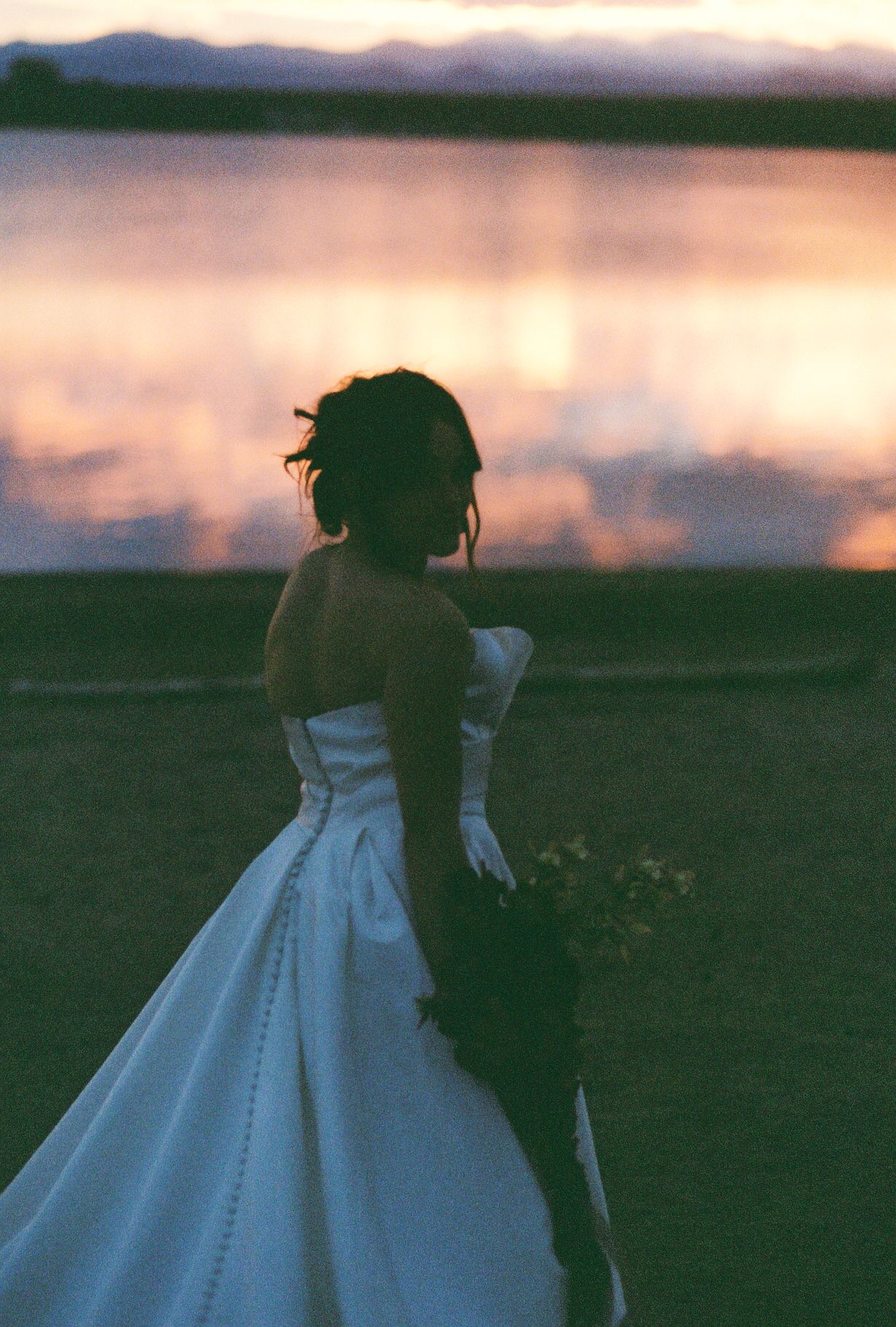 Bride in classic white ballgown silhouetted against a sunset sky.
