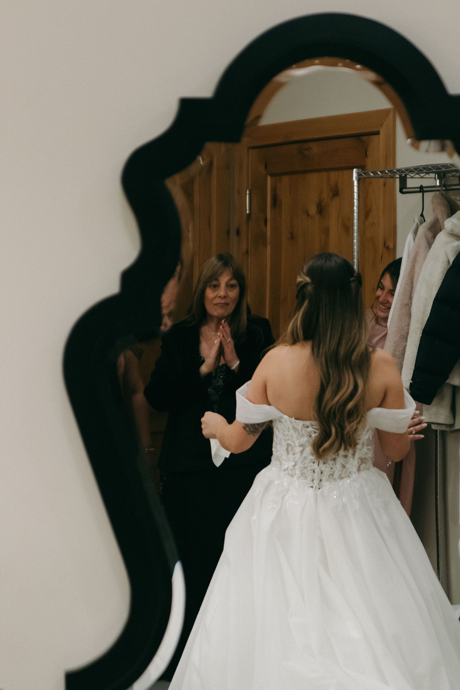 An elegant wedding dress captured in an ornate mirror's reflection during final preparations.