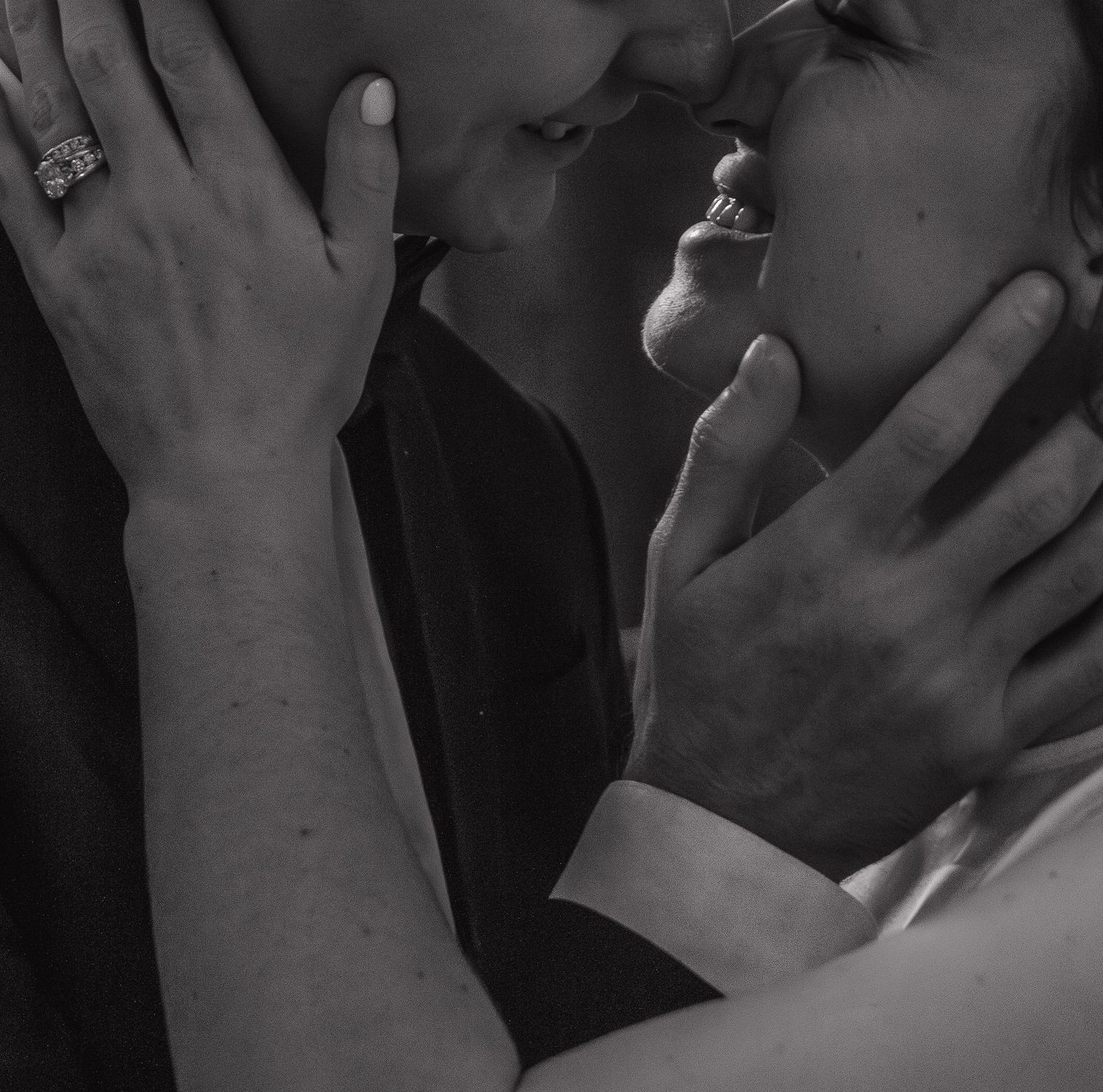 Black and white photo of hands gently touching in an intimate and artistic composition.