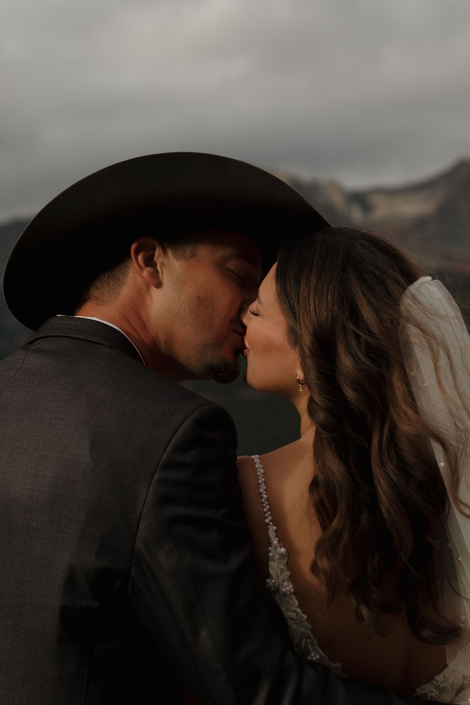 A romantic silhouetted wedding moment captured against a moody mountain backdrop.