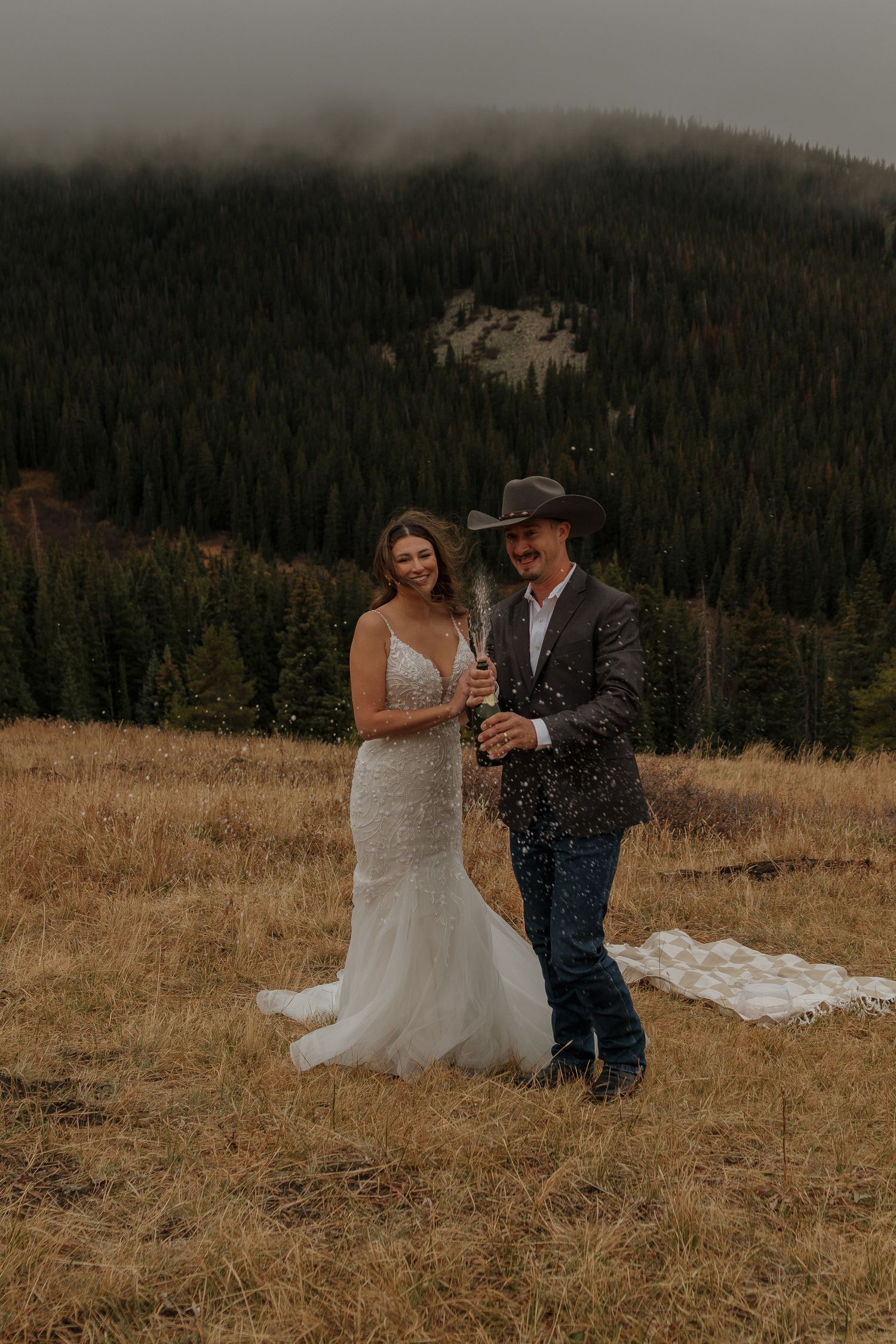 A couple dances together in a mountain meadow during their rustic outdoor wedding.