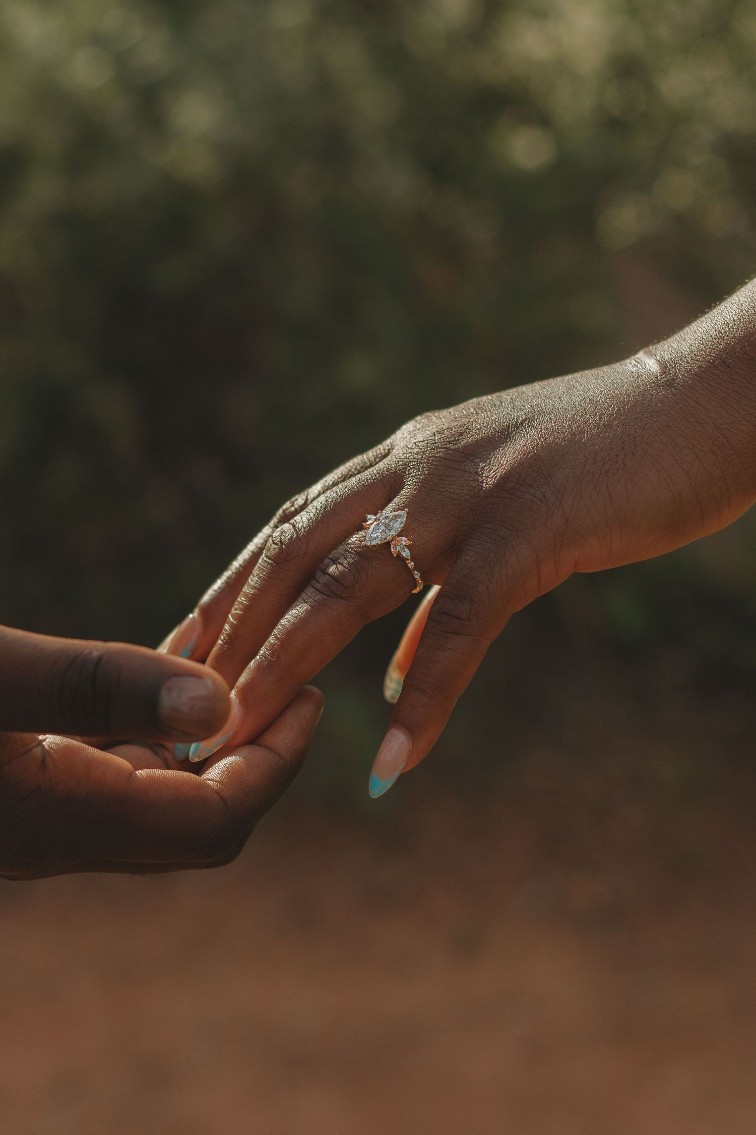 Close-up shot of hands wearing turquoise and silver rings against a blurred natural background.
