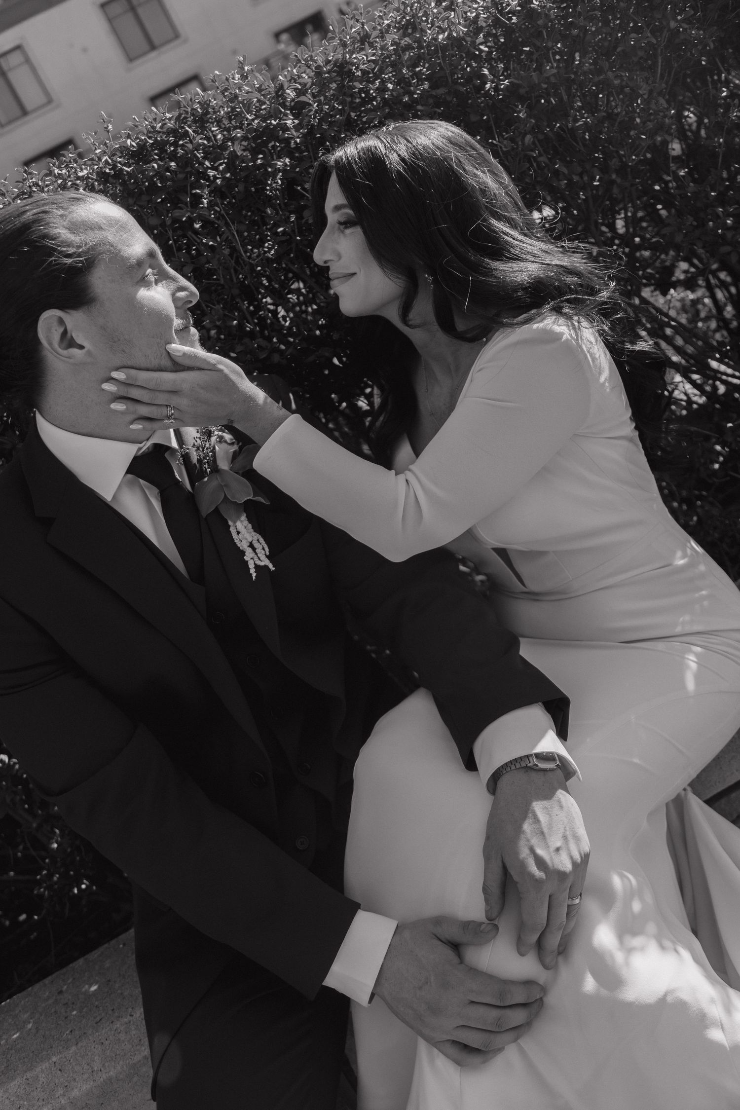 Black and white photo of groom lifting bride as they share a romantic moment outdoors.
