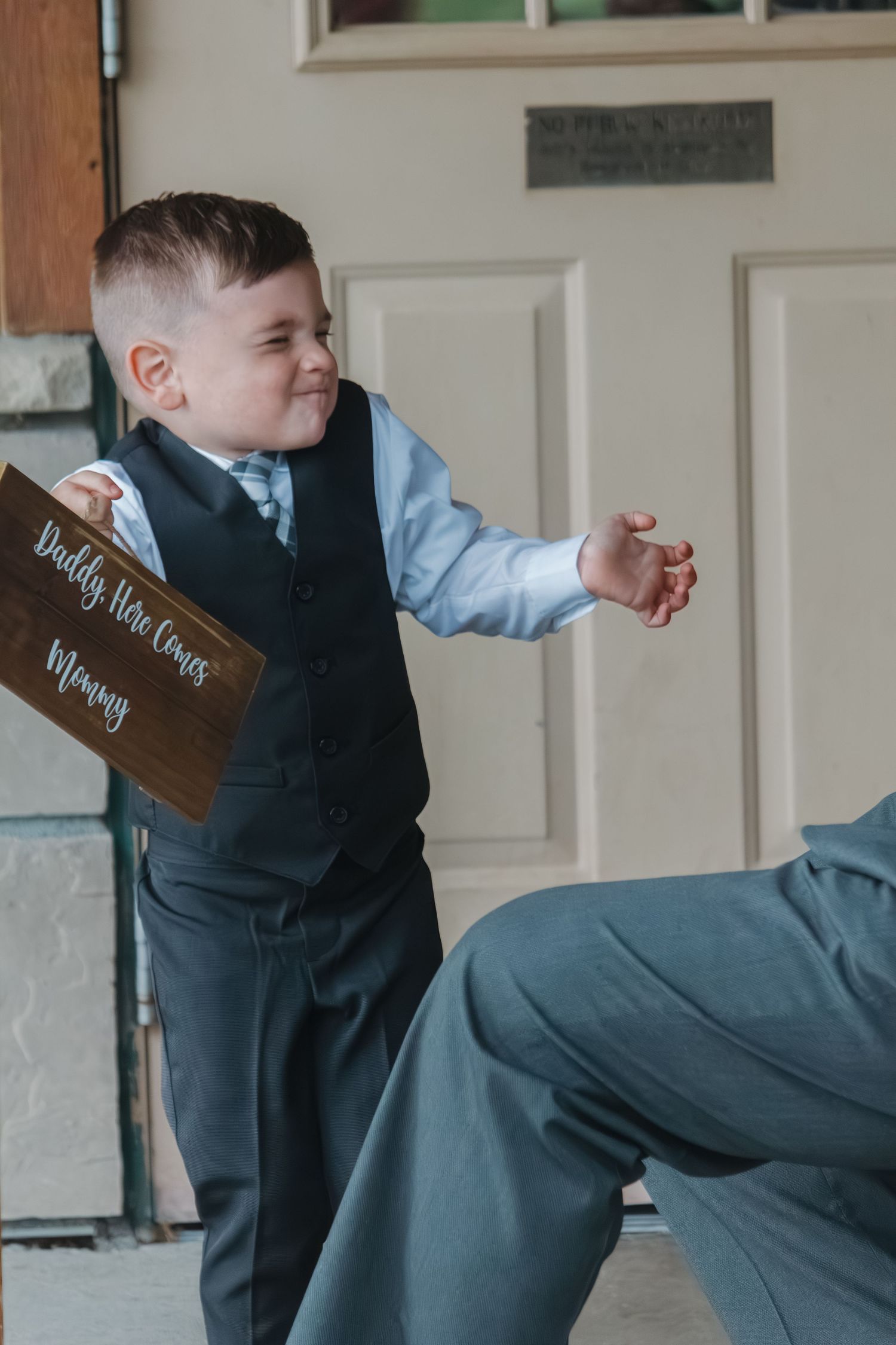 Young ring bearer in formal attire striking playful poses indoors.