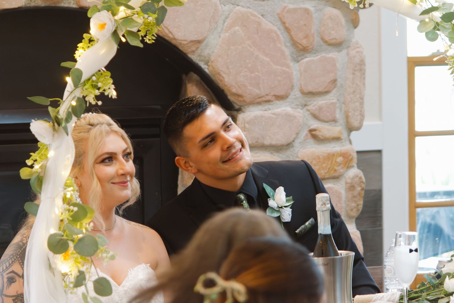 A couple shares a joyful moment under floral arch decorations at their wedding ceremony.