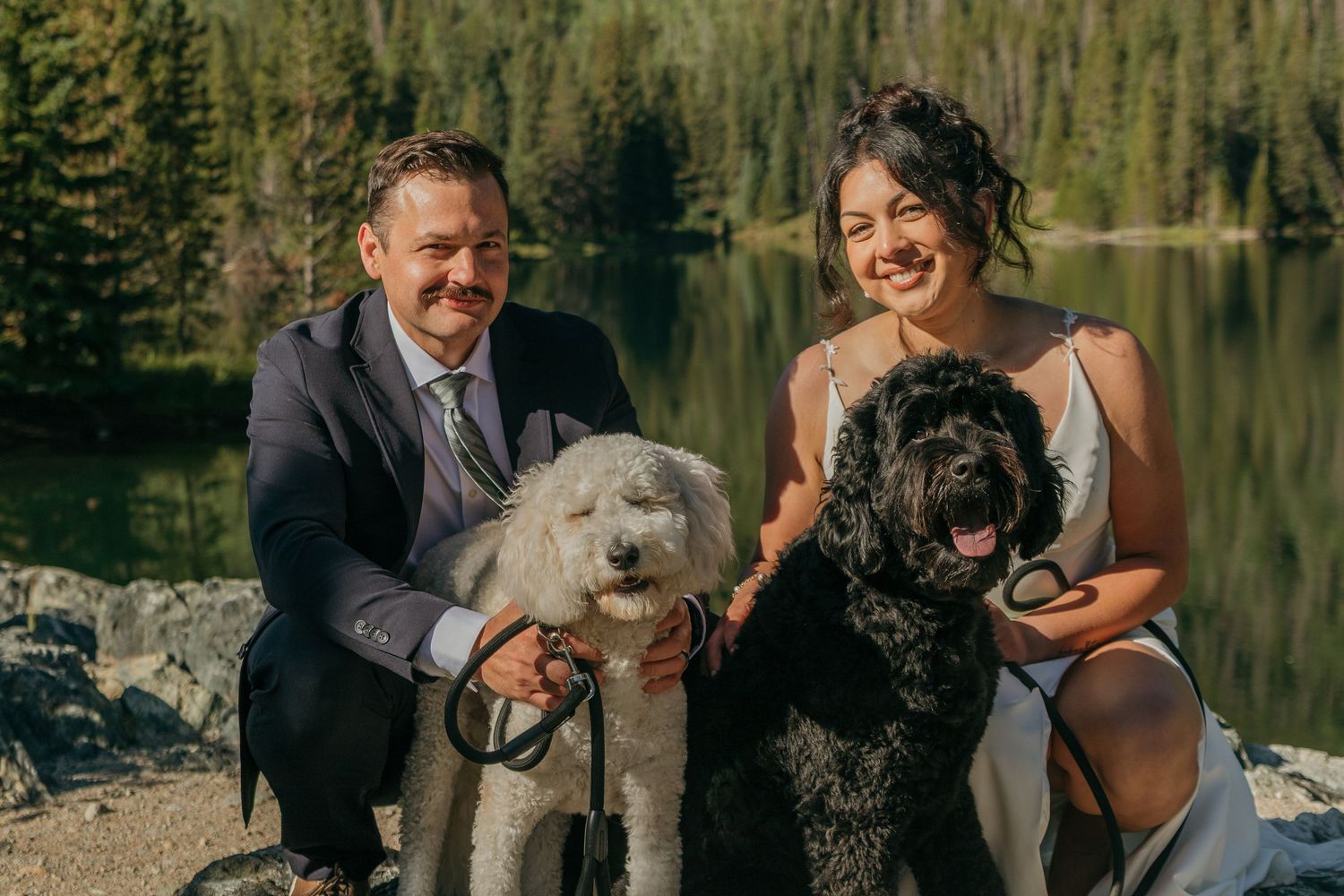 A cheerful group portrait with pets on rocks by a mountain lake.