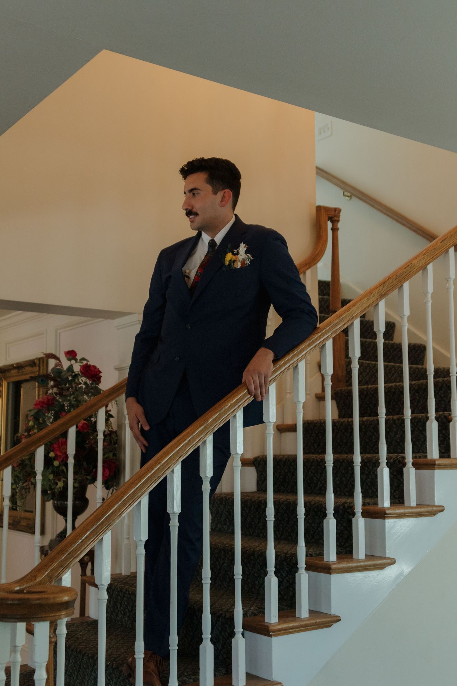 Groomsmen pose on a wooden staircase with white balusters in classic formal wear.