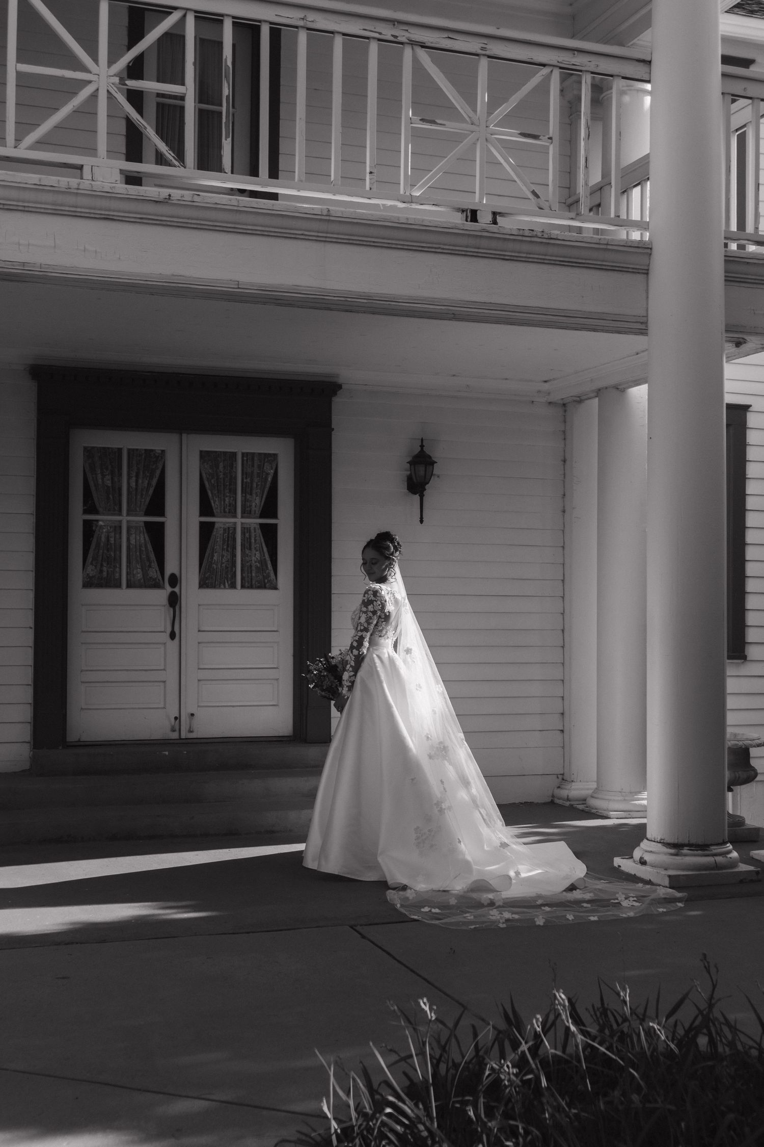White wedding dress with long train photographed on colonial style porch.