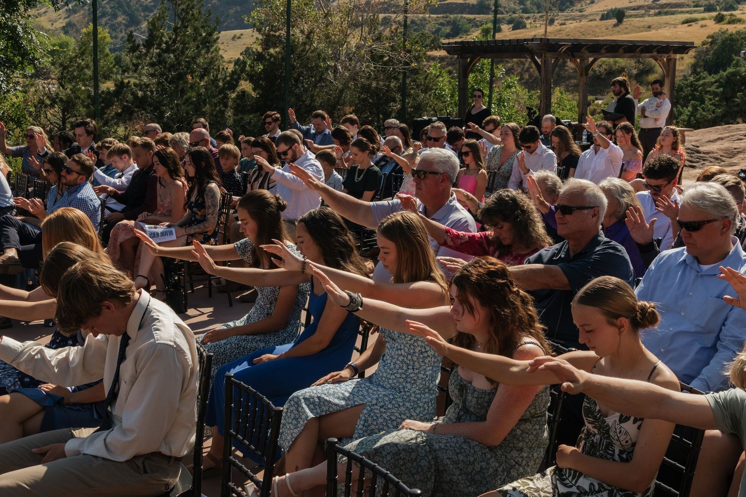 Wedding guests seated in rows during an outdoor ceremony with mountain views.
