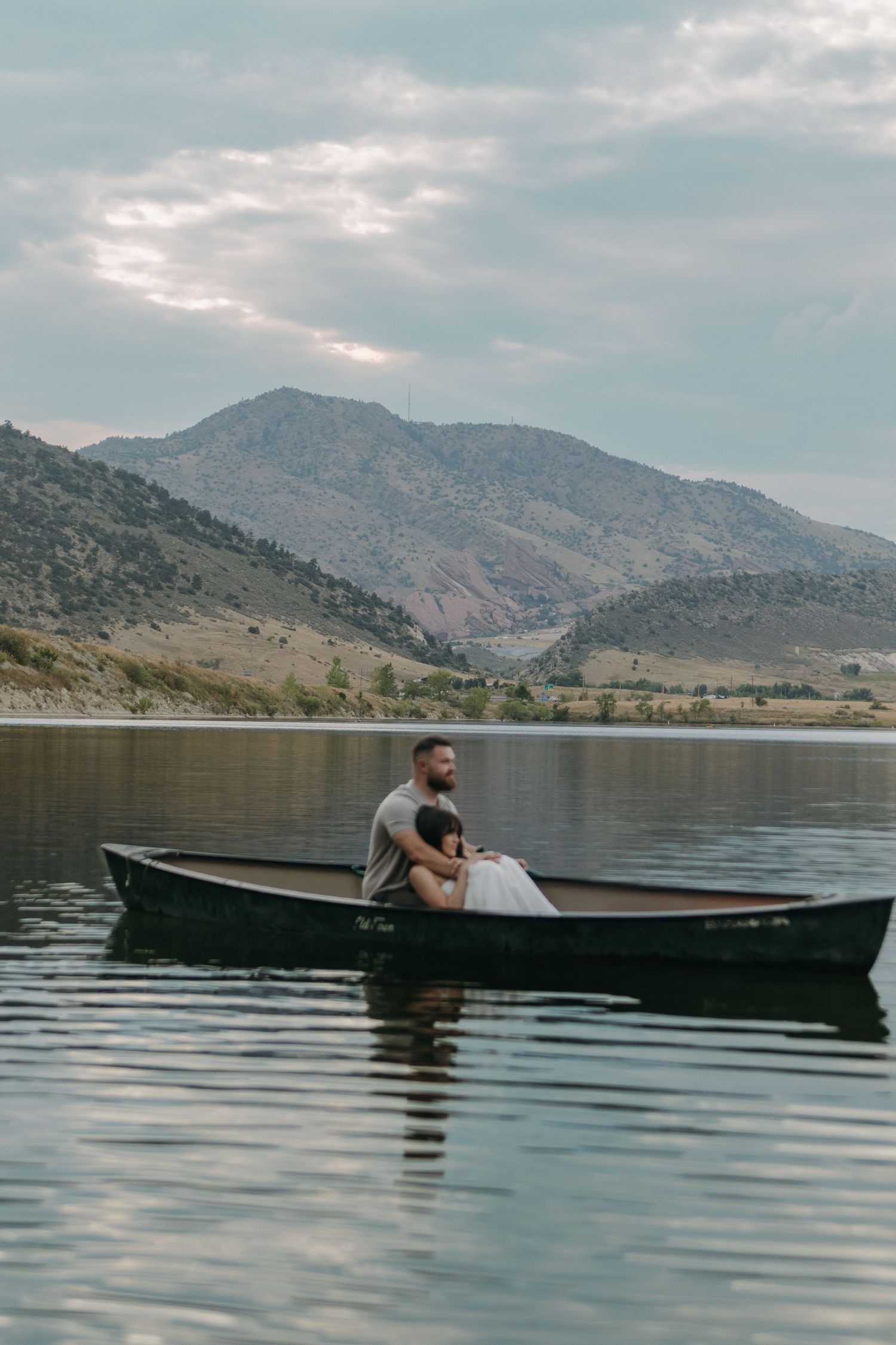 A peaceful scene of two people relaxing in a small boat against a backdrop of scenic mountain views.
