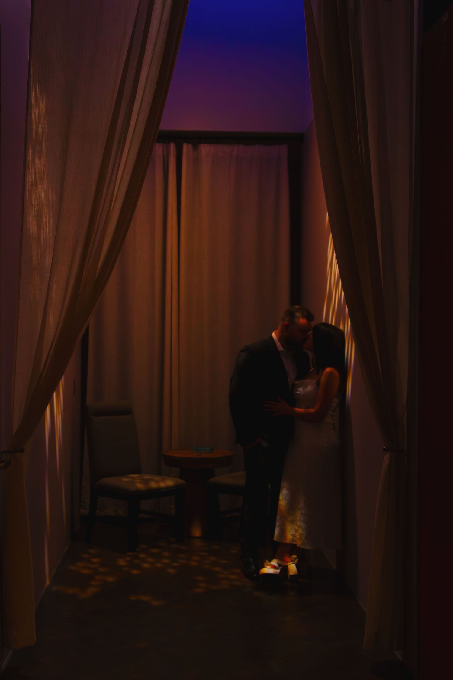 Dark interior room with dramatic lighting and curtains casting shadows along a window.