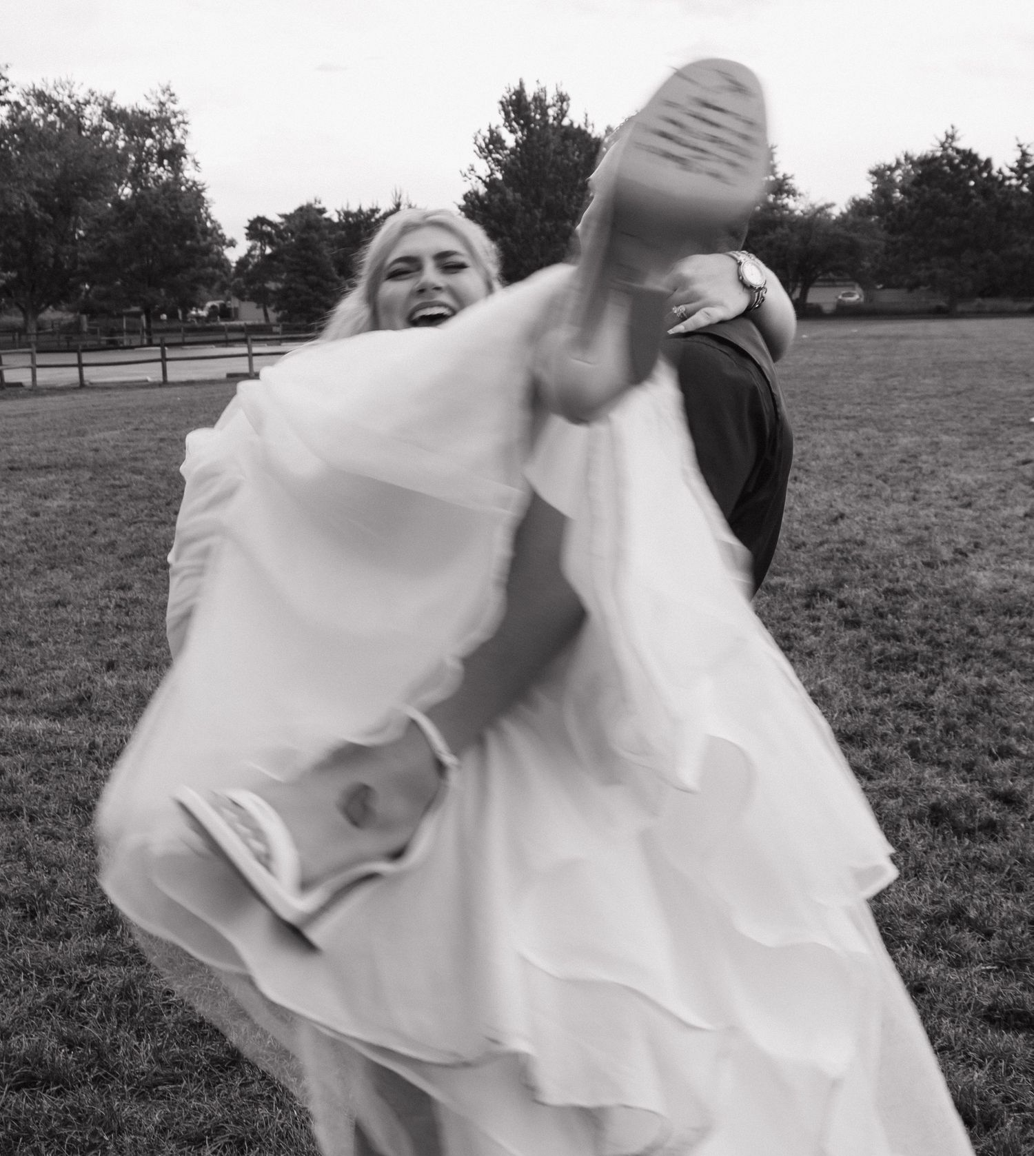 A flowing white dress twirls gracefully in a series of black and white photos taken in an outdoor field setting.