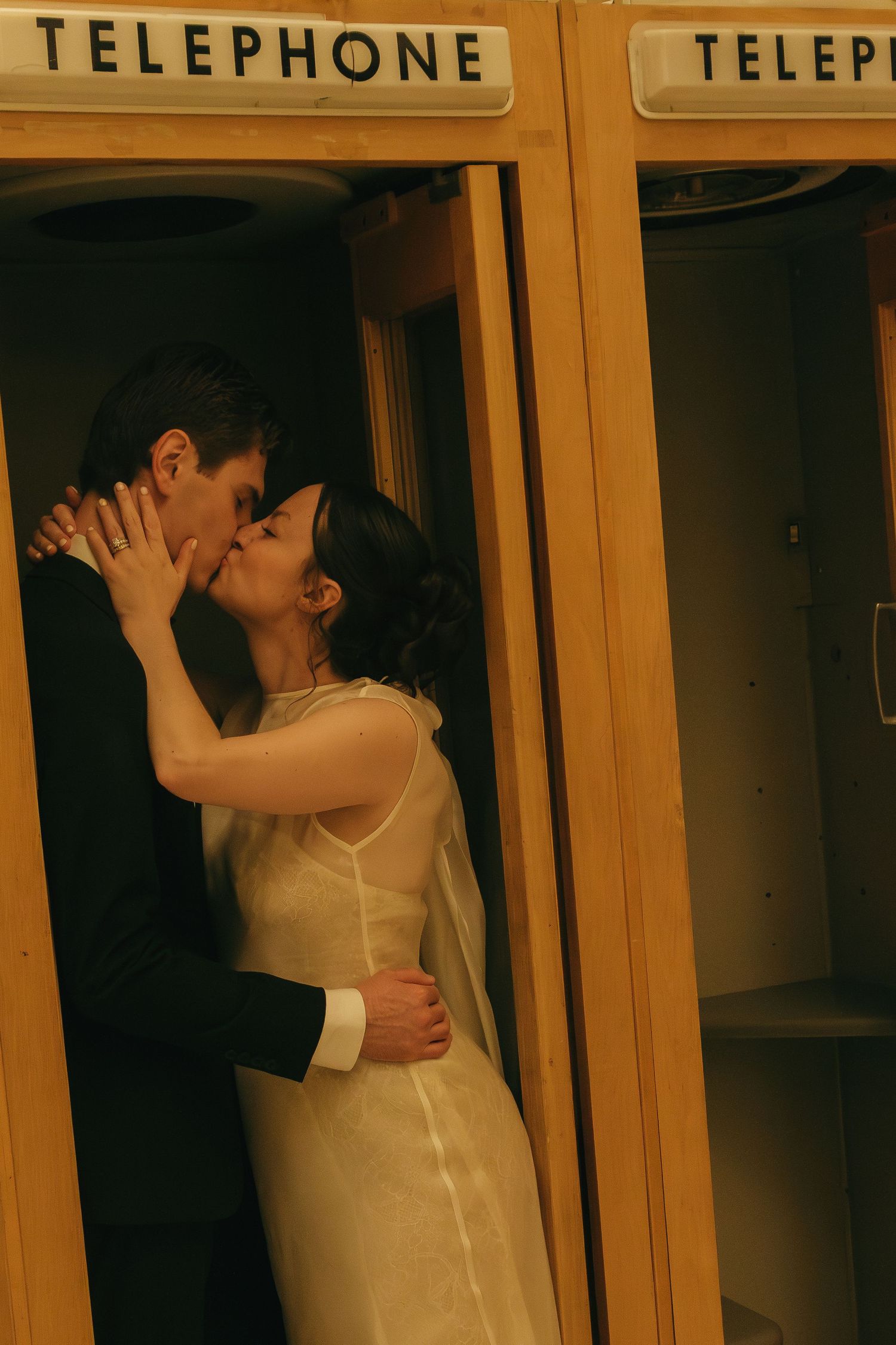 Romantic moment between newlyweds in front of vintage telephone booth.