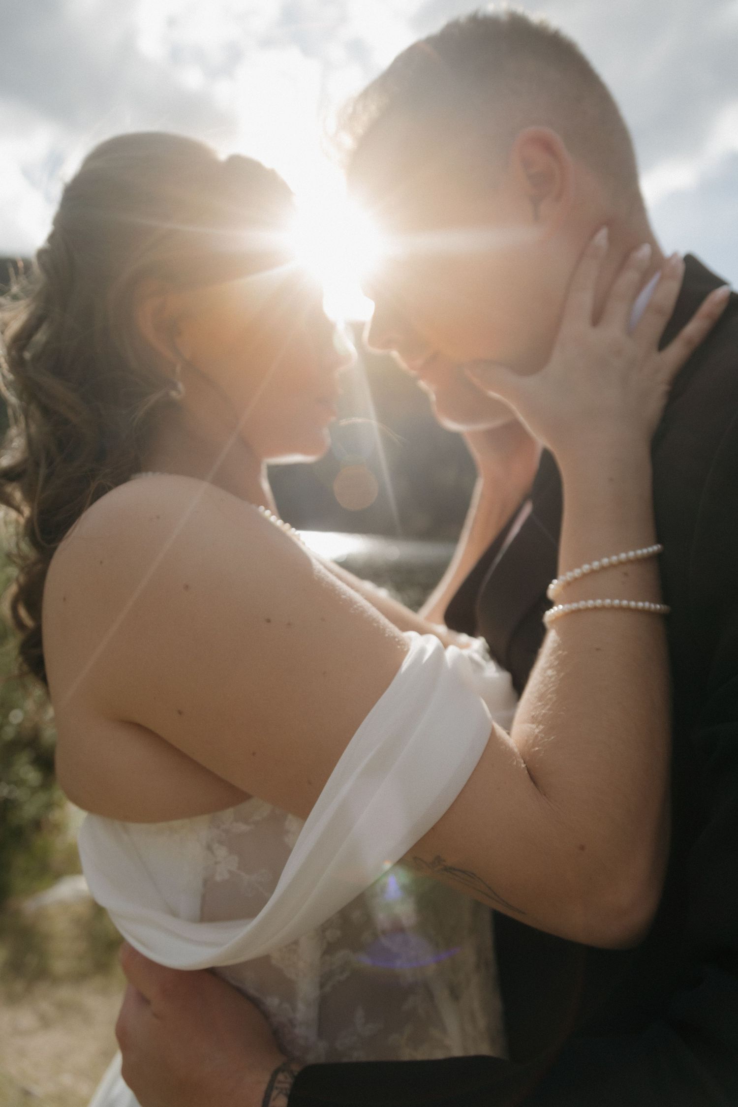 Bride and groom share an intimate moment backlit by golden sunlight during their outdoor mountain elopement.