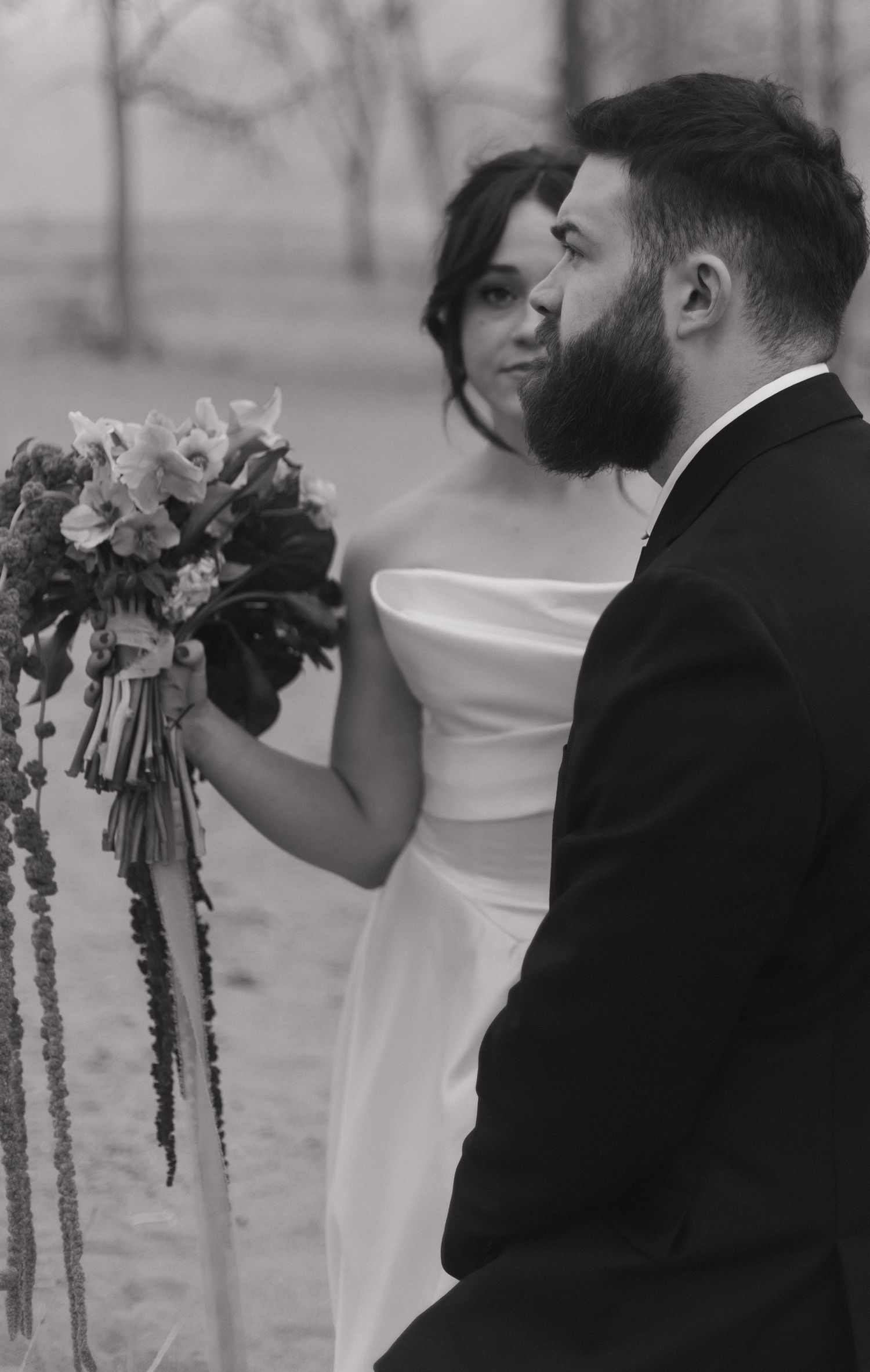 A black and white wedding photo featuring a stunning bouquet with cascading flowers and ribbons.