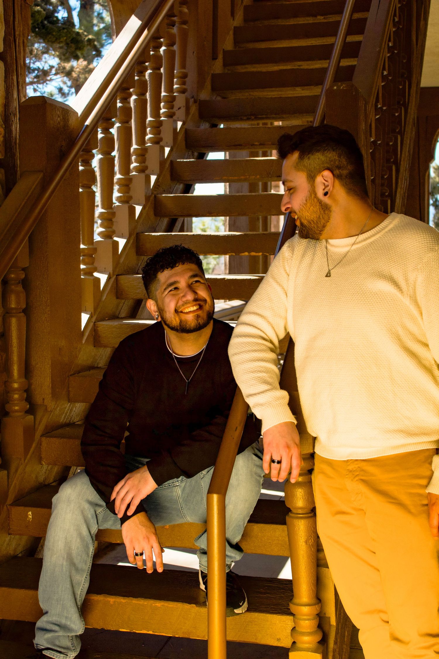 Two people share a joyful moment on wooden stairs with natural lighting.