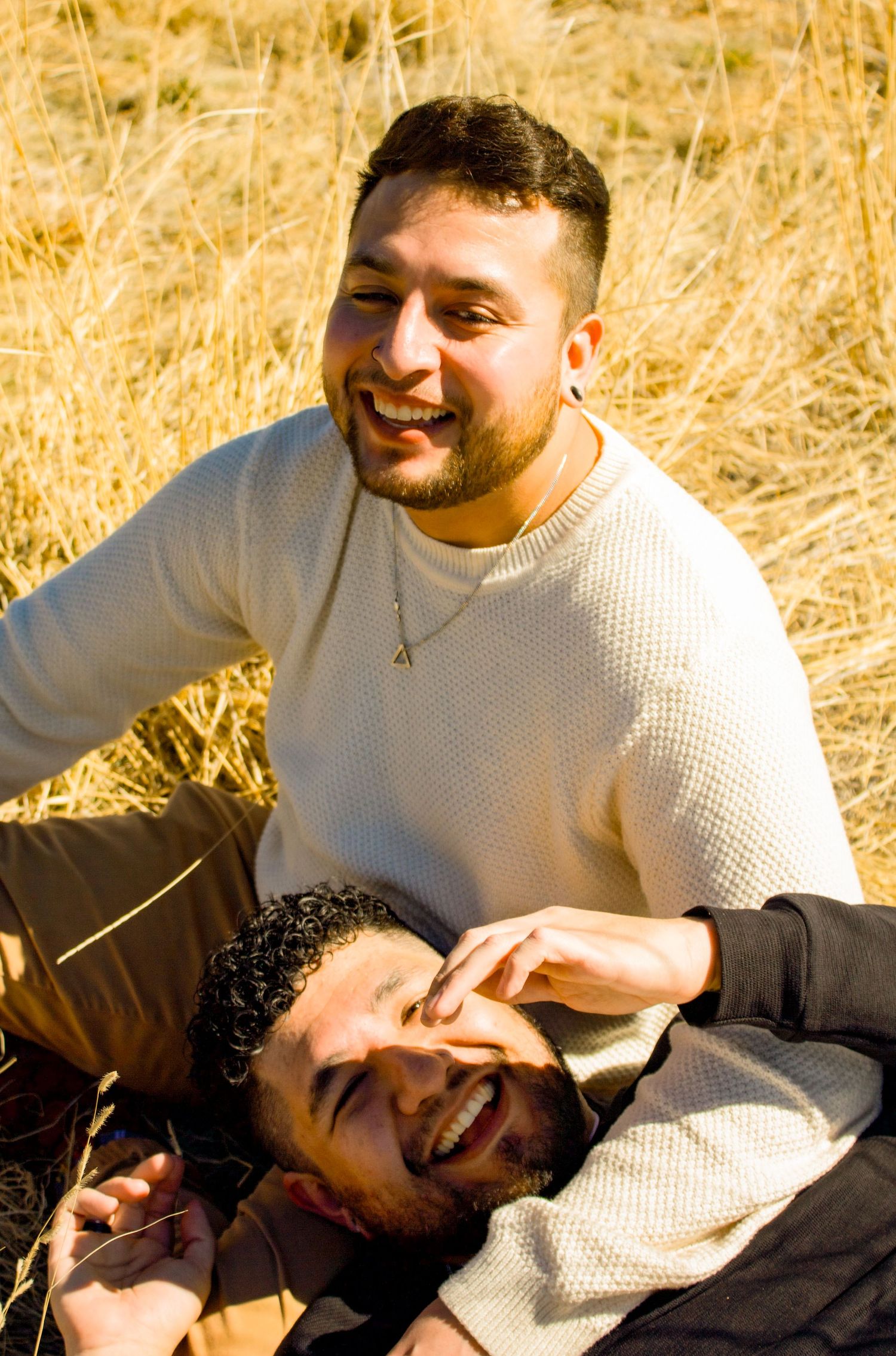 Candid moment captured of two people laughing together in sunlit field.