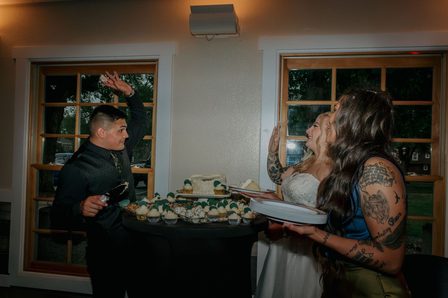 Wedding reception venue with windows and ambient lighting during cake-cutting ceremony.