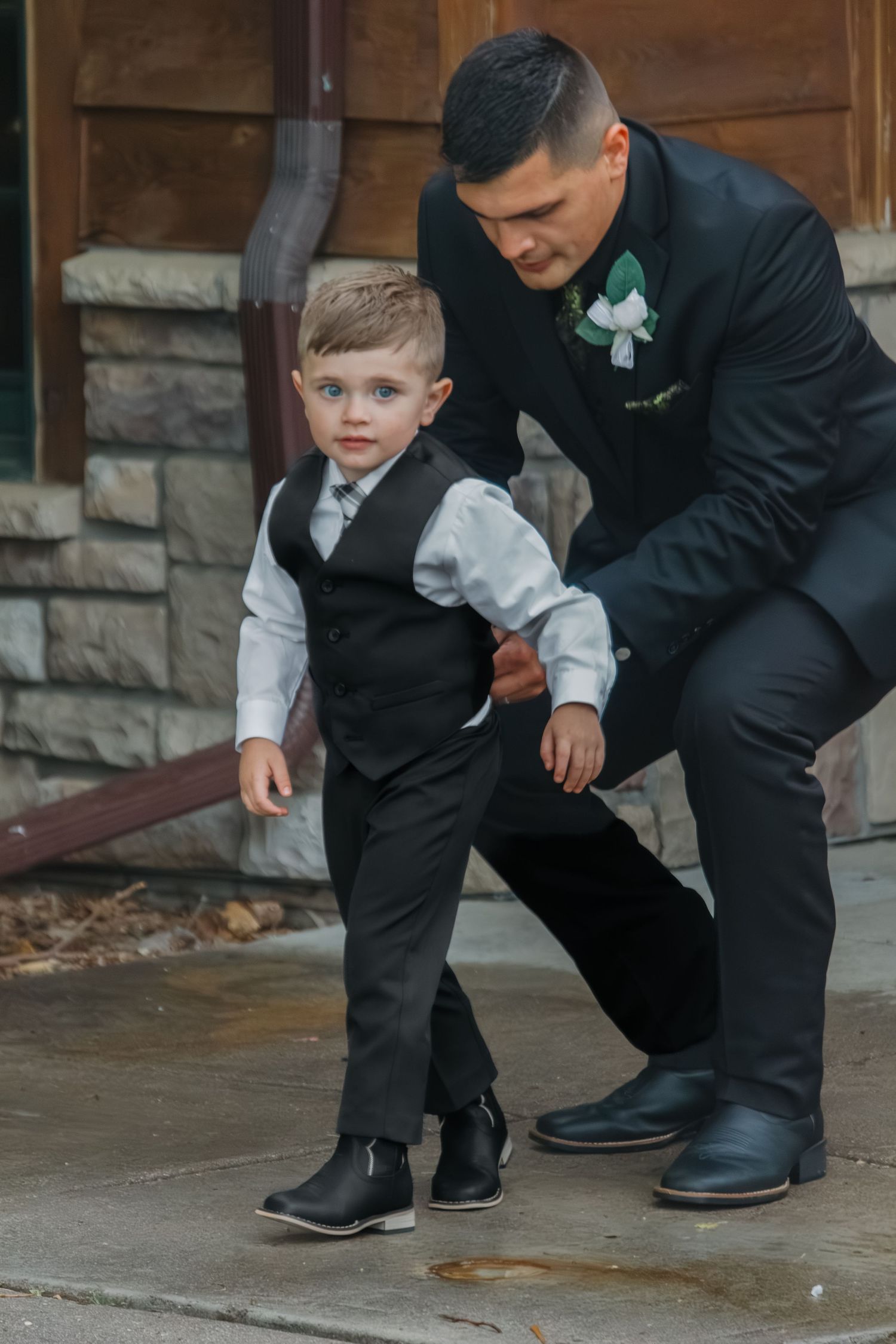 Young ring bearer getting help with his formal shoes before a wedding ceremony.