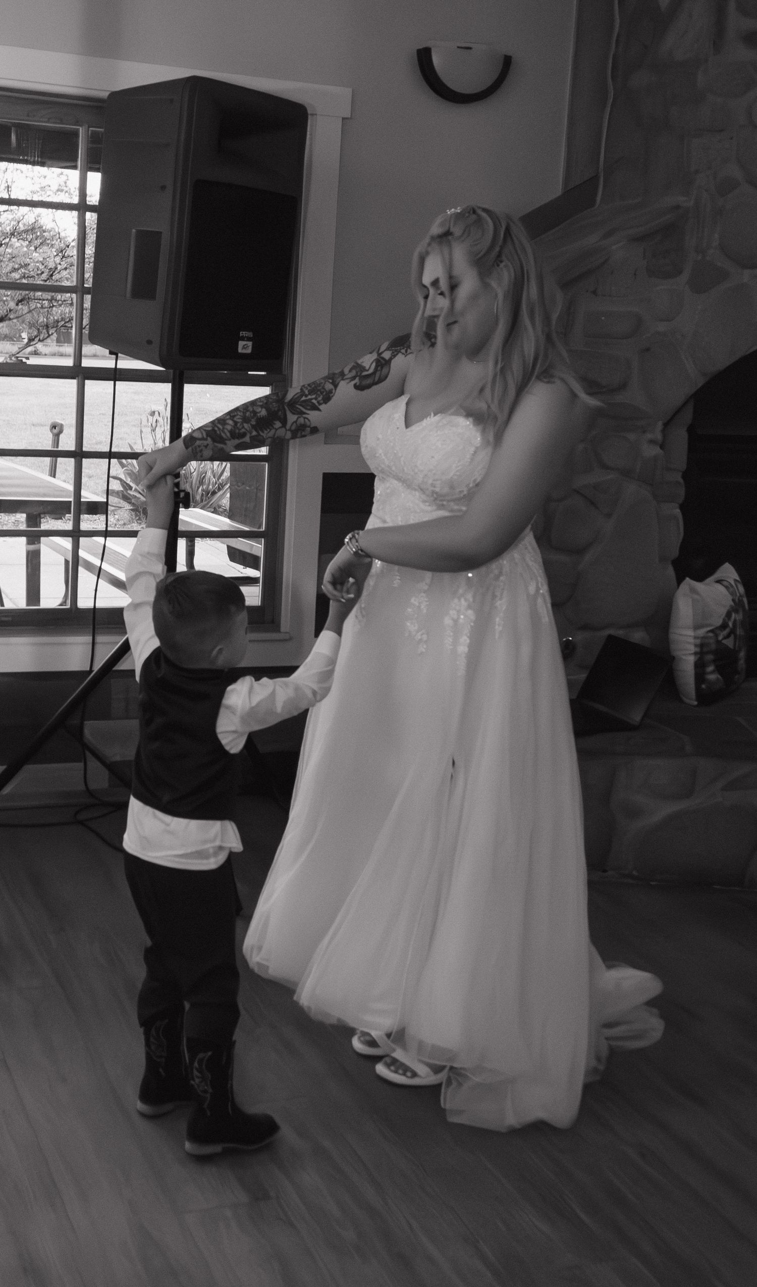 Dancing celebration at wedding reception with white dress swirling on wooden floor.