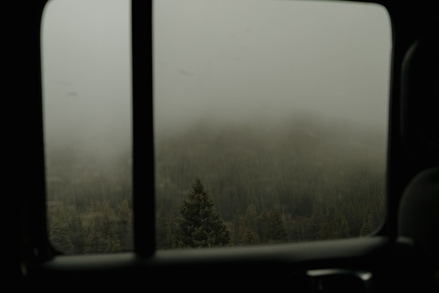 A misty mountain landscape view through a window frame.