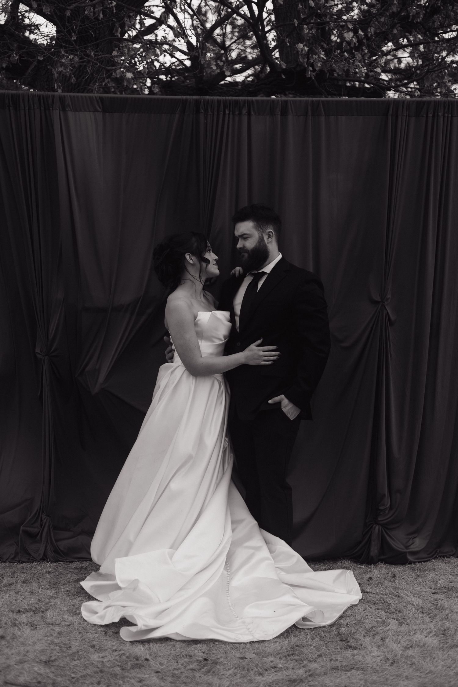 Romantic first look sequence between couple with flowing white wedding dress against dark backdrop.