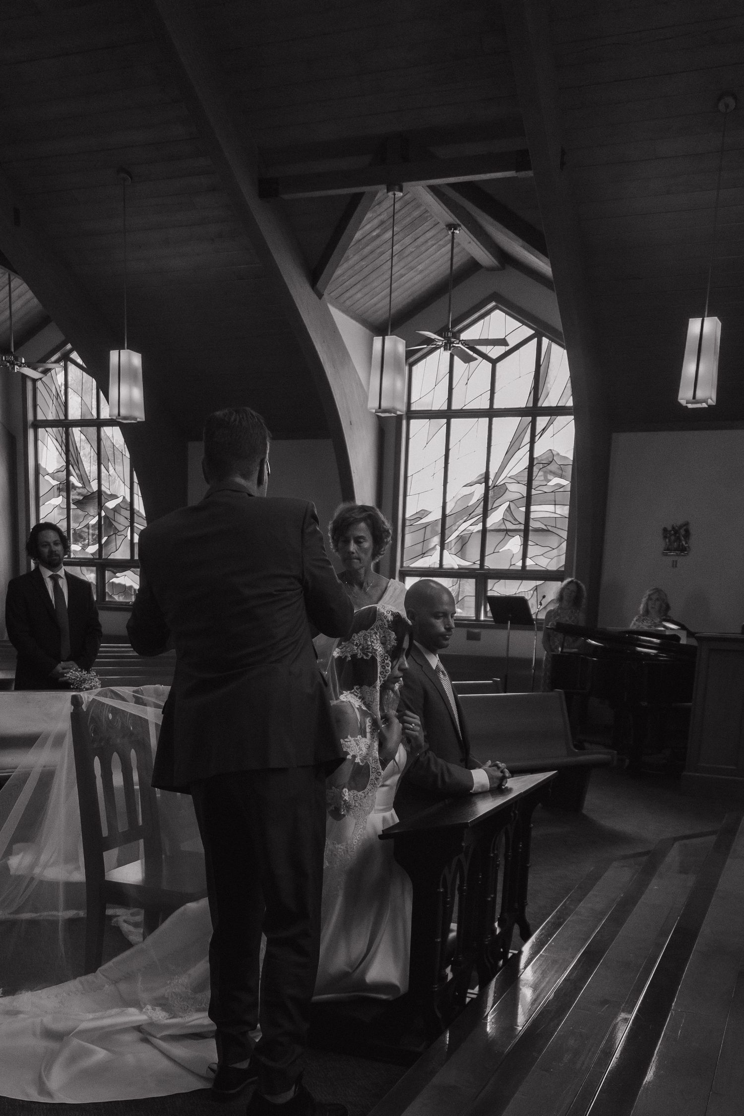 A bride and groom sign wedding documents at the altar of a rustic mountain church.