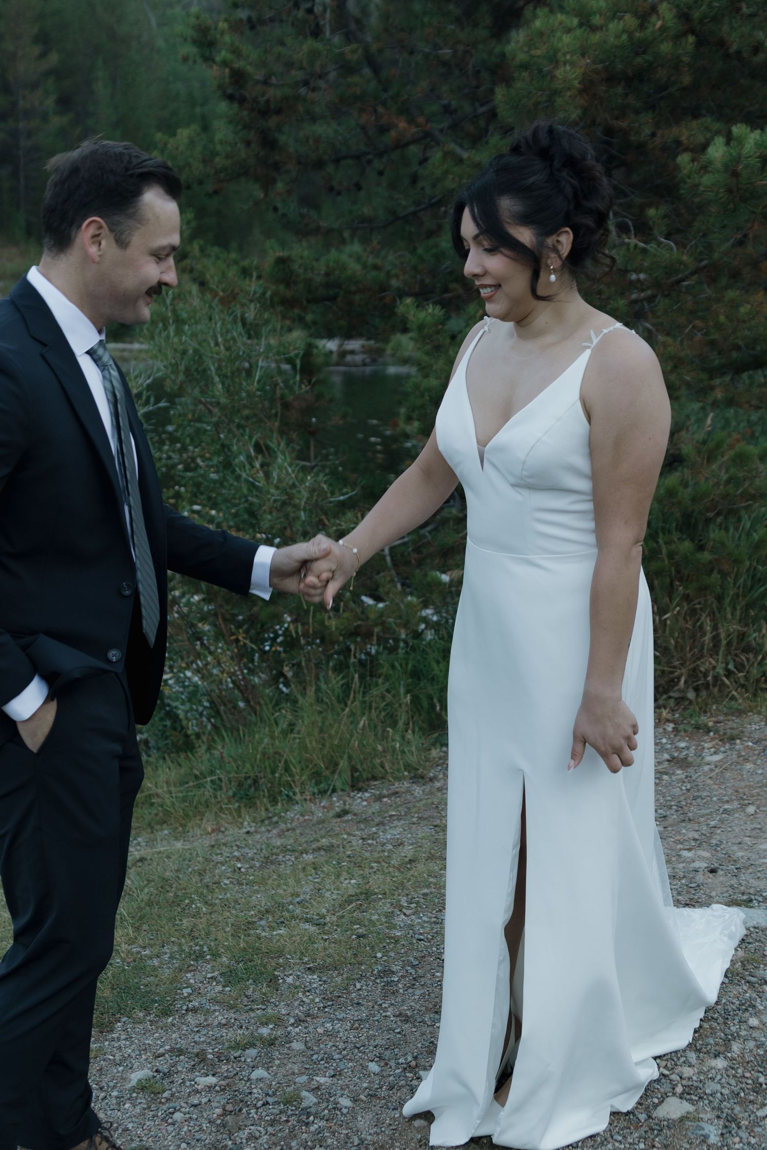 A series of black and white wedding photos showing a couple walking and interacting on a gravel path in a natural setting.