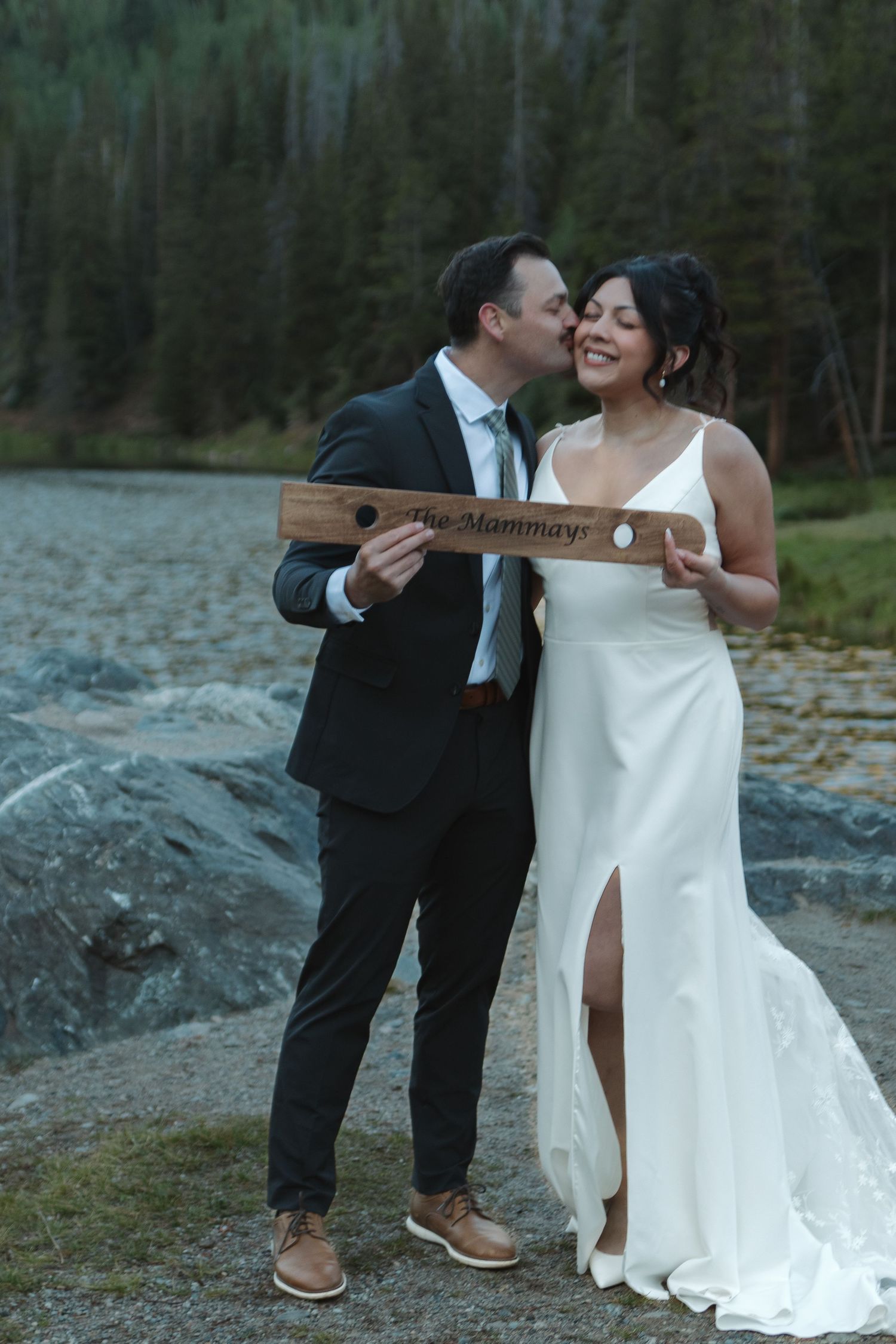 A playful wedding moment with a couple sharing laughter on a rocky mountain landscape.