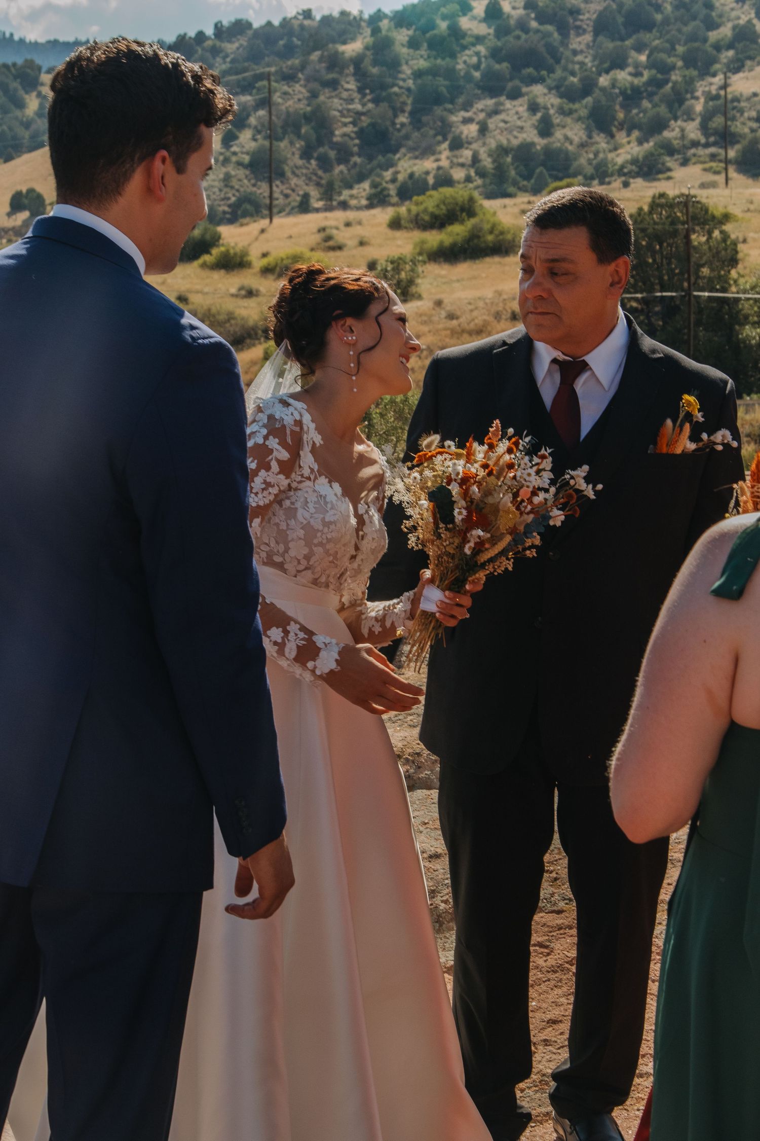 Wedding party members gather during outdoor ceremony with mountains in the background.