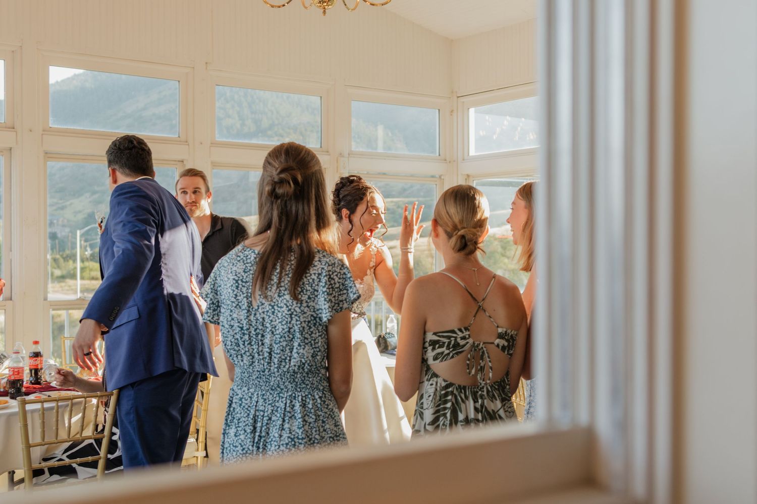 Wedding celebration in a bright venue with mountain views visible through large windows.