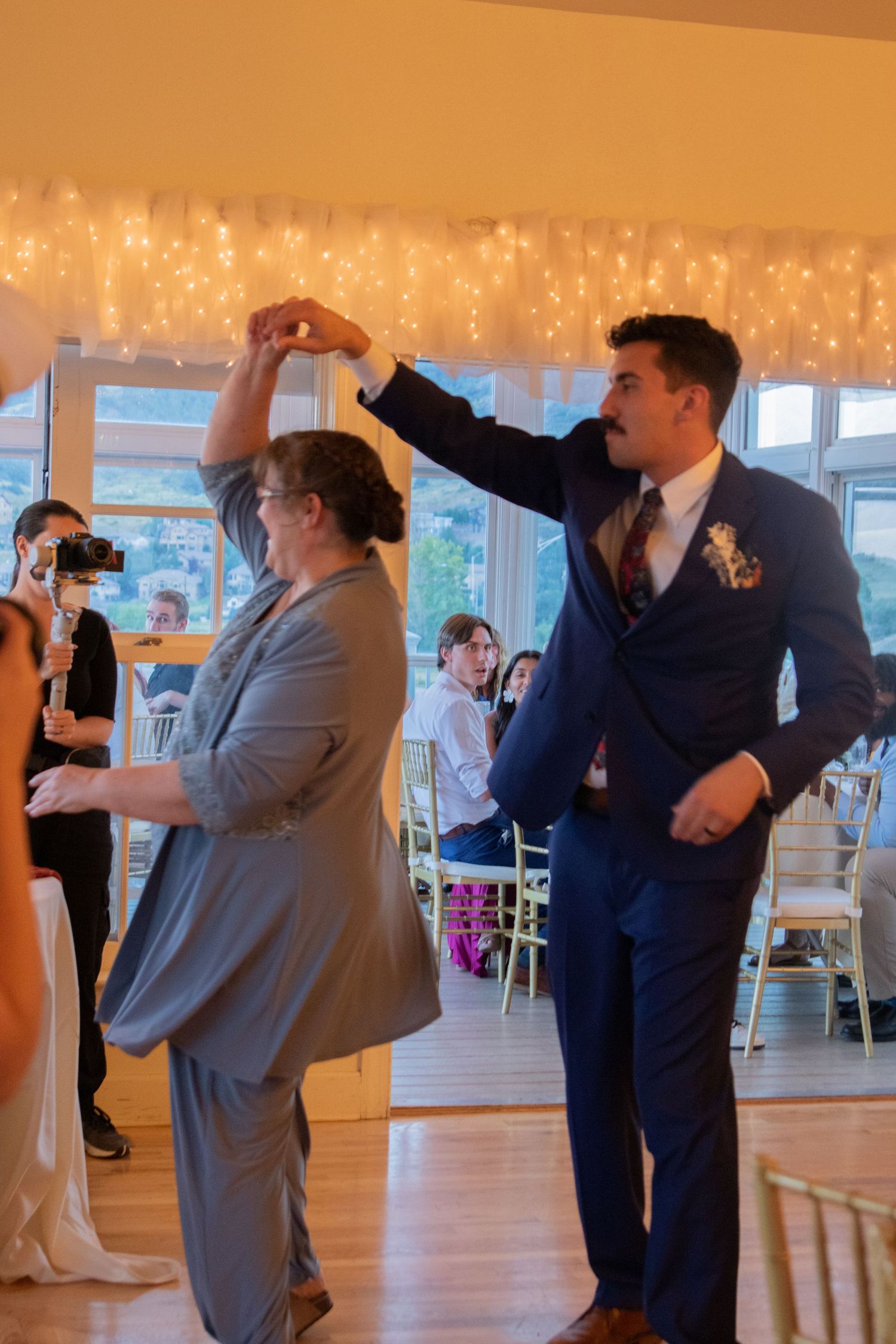 Wedding guests dancing at reception with twinkle lights decorating the background.