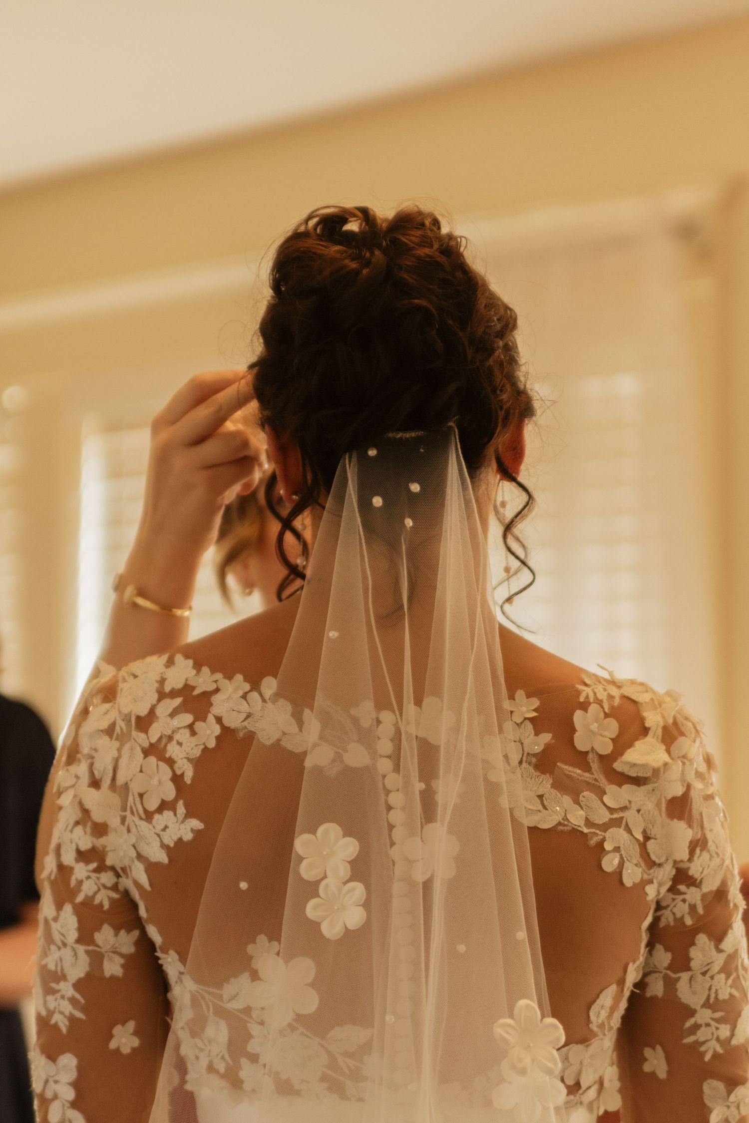 Close-up shots of a delicate lace wedding veil with floral appliques being adjusted.