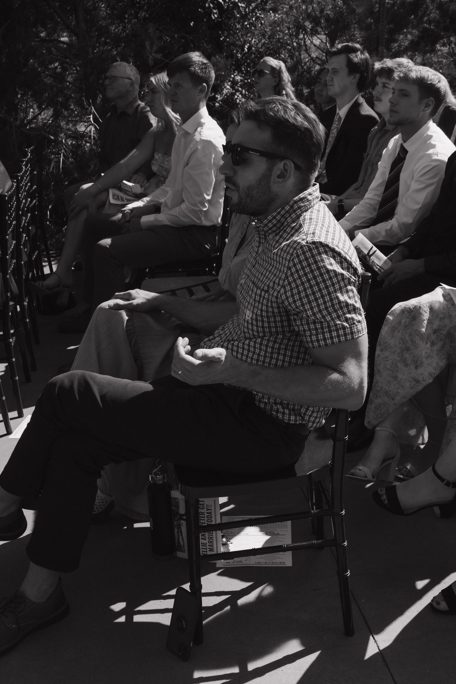 Wedding guests seated in rows during an outdoor ceremony in black and white.