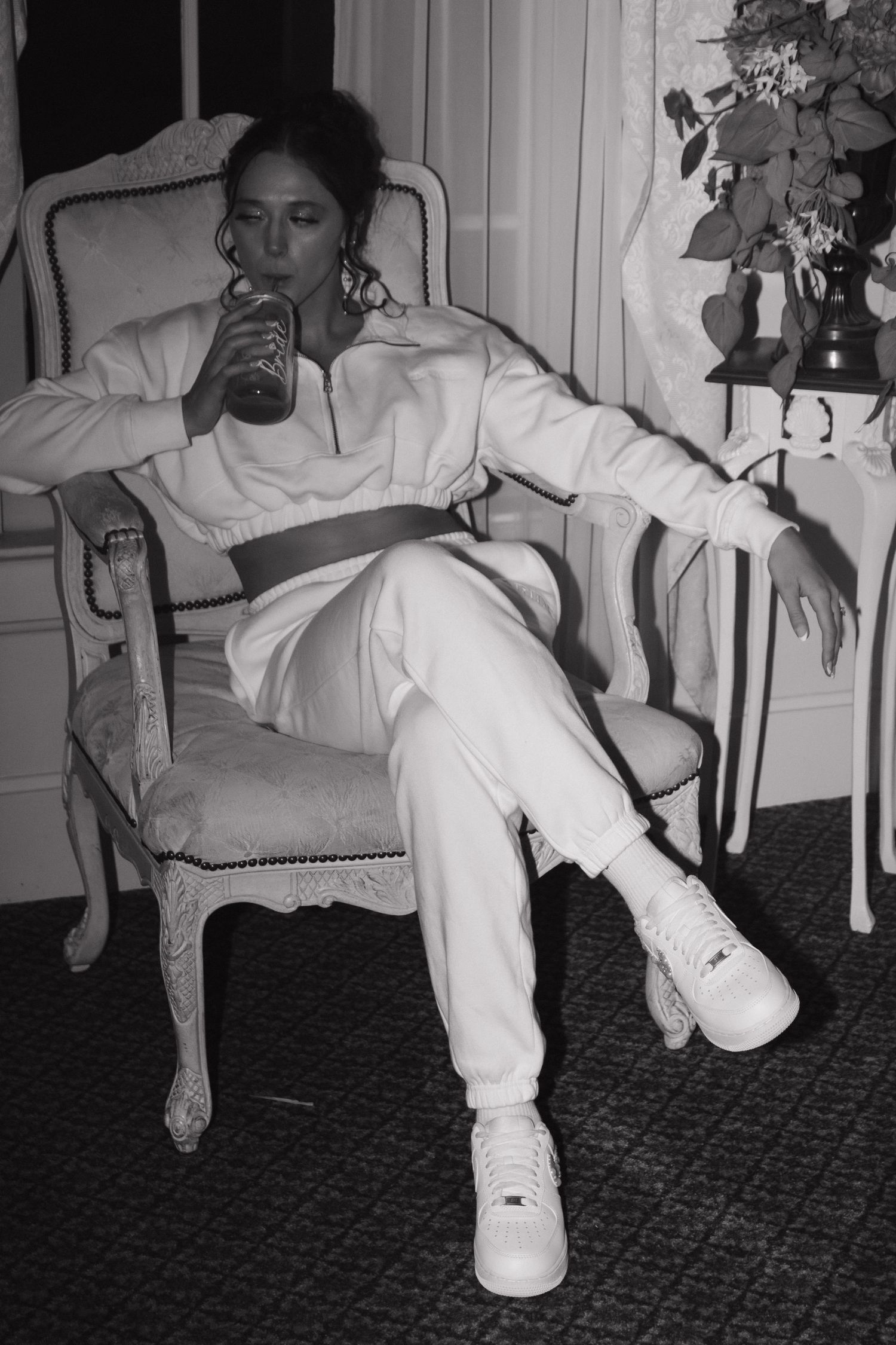 Black and white series shows groom adjusting shoe while seated indoors.
