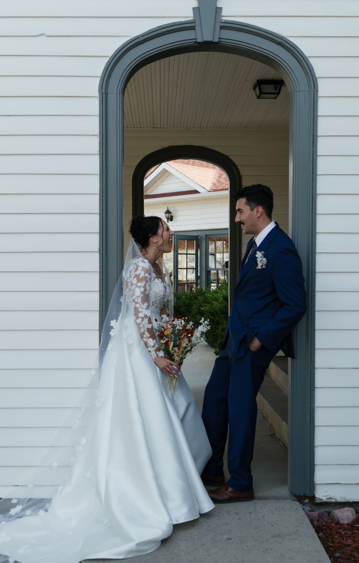 Romantic wedding couple shares tender moments in an elegant white archway.