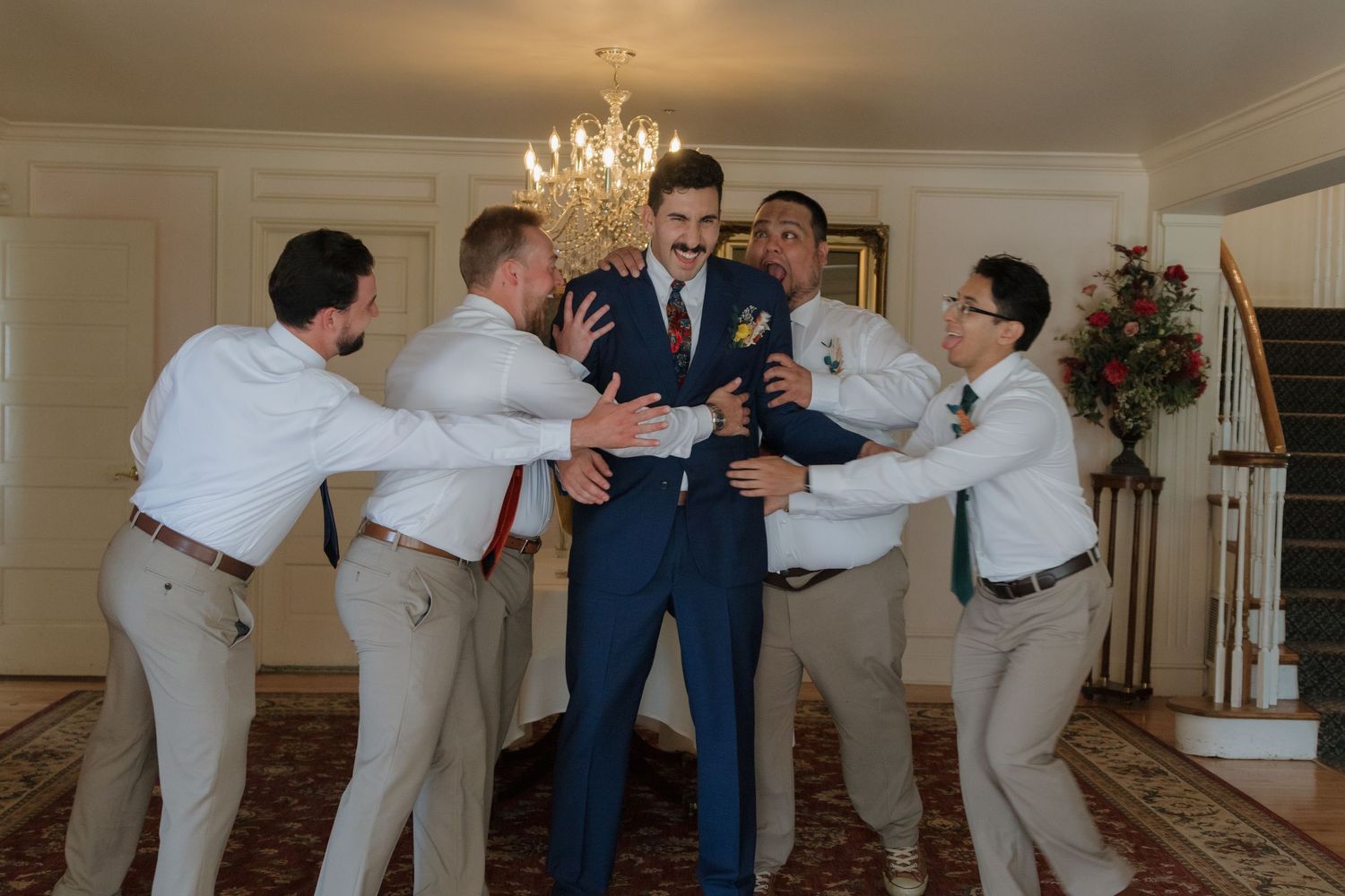 Groomsmen in light suits performing fun poses for wedding photos.