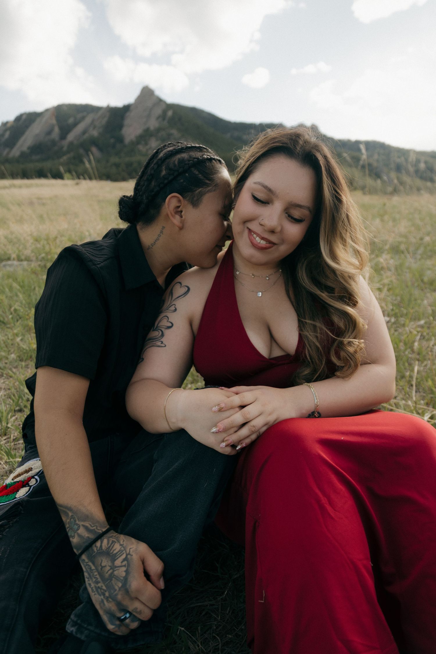 A couple shares a tender moment in a field with the Flatirons of Boulder, Colorado in the background.