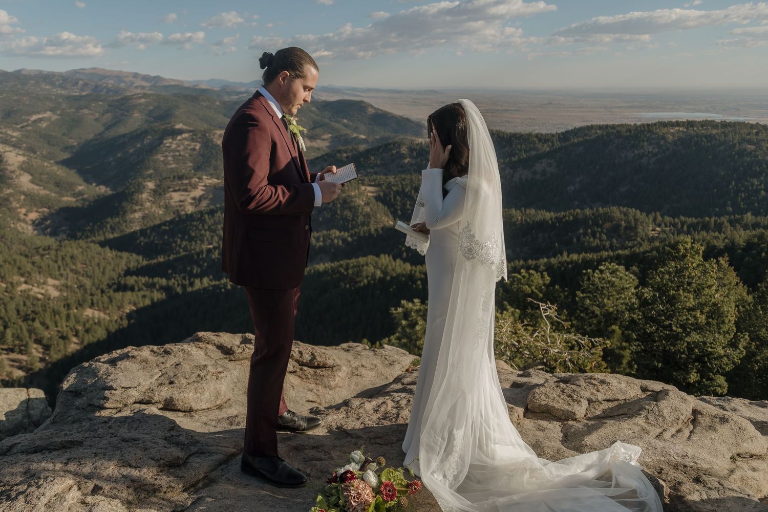 Couple exchanges vows on dramatic rocky mountain overlook with sweeping valley views below.