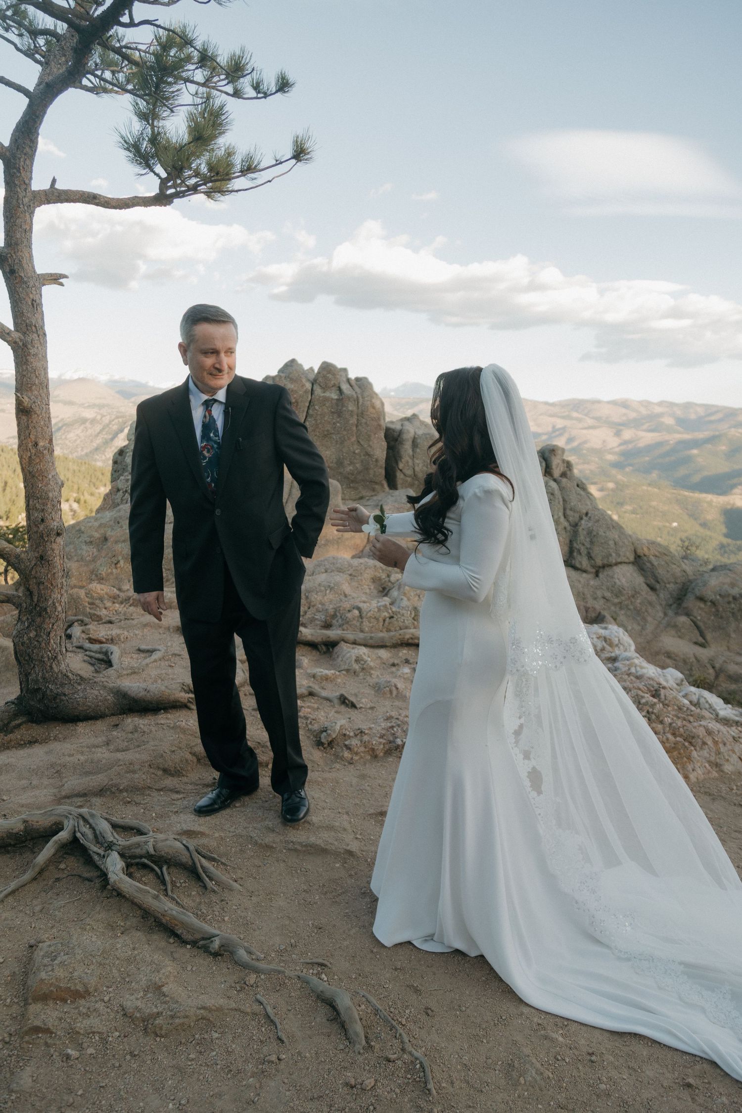 Bride and groom exchange vows on a rocky mountain overlook with scenic valley views.