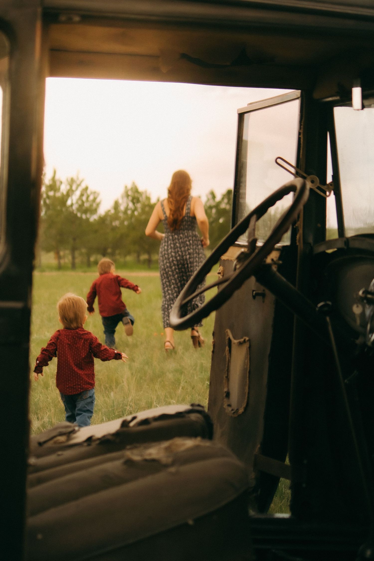 View through vintage car window of people walking in a sunlit field.