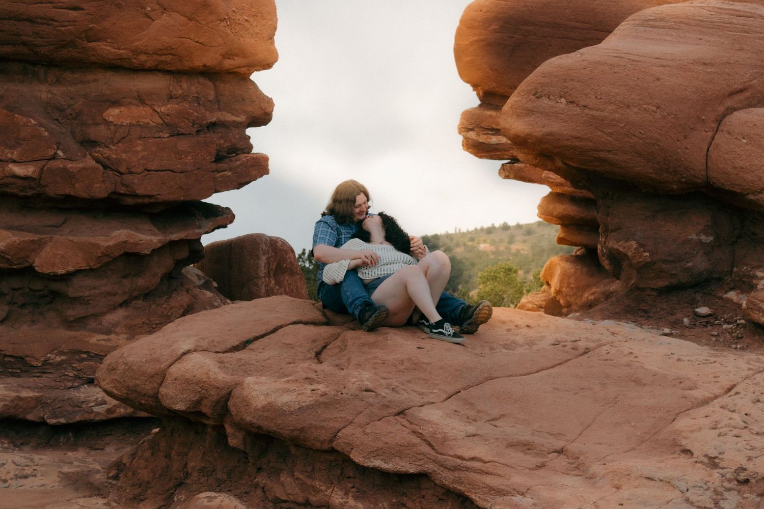 Wide angle shot of couple sharing intimate moment in desert rock alcove.