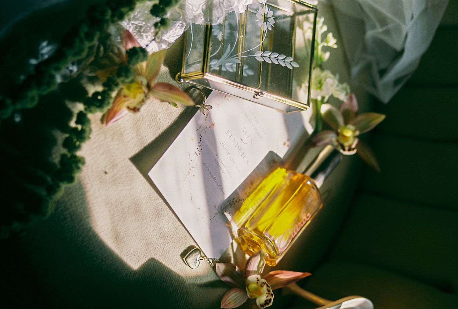Wedding details with perfume bottles and stationery bathed in natural sunlight and delicate shadows.