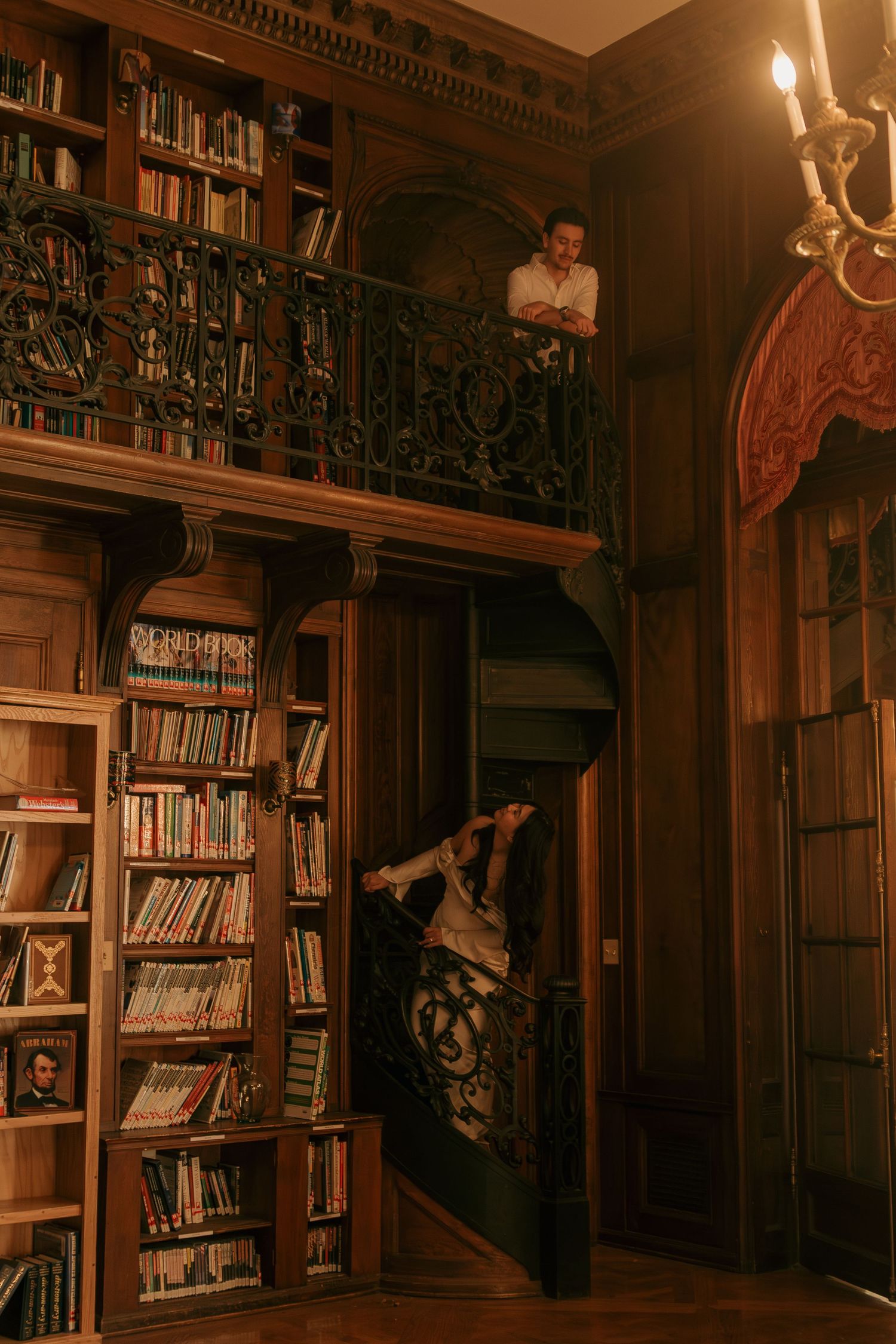 Ornate vintage library interior with dark wood bookshelves, spiral staircase, and warm lighting creating a cozy atmosphere.