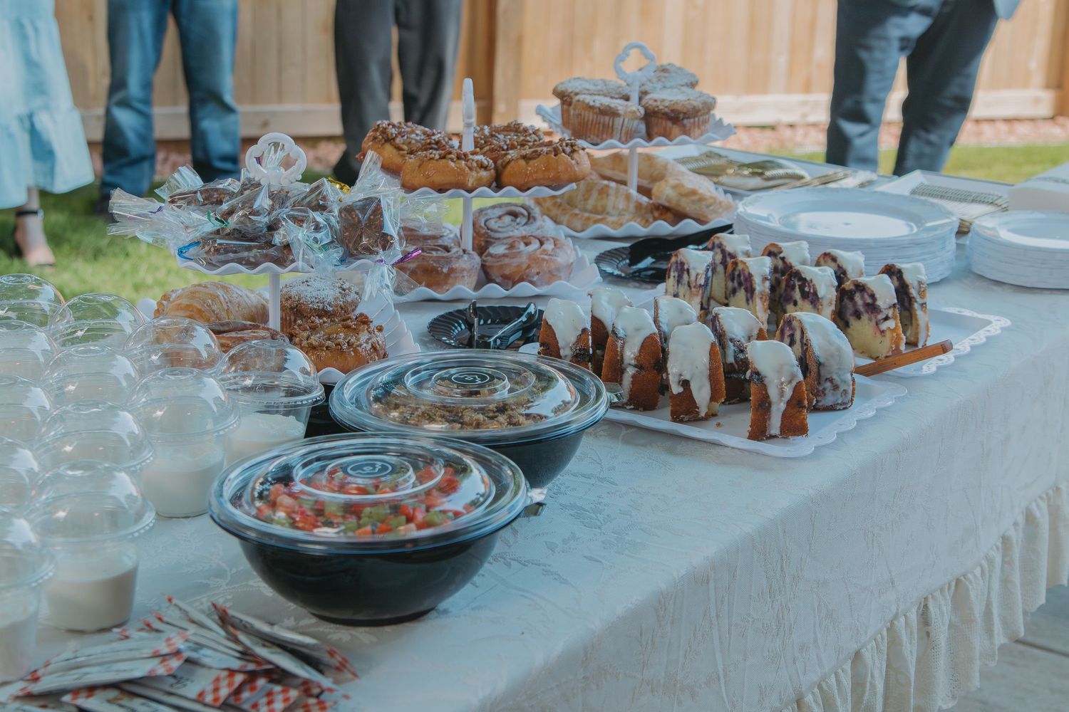 A long banquet table covered in white linens displays an elegant spread of appetizers and desserts for an event.