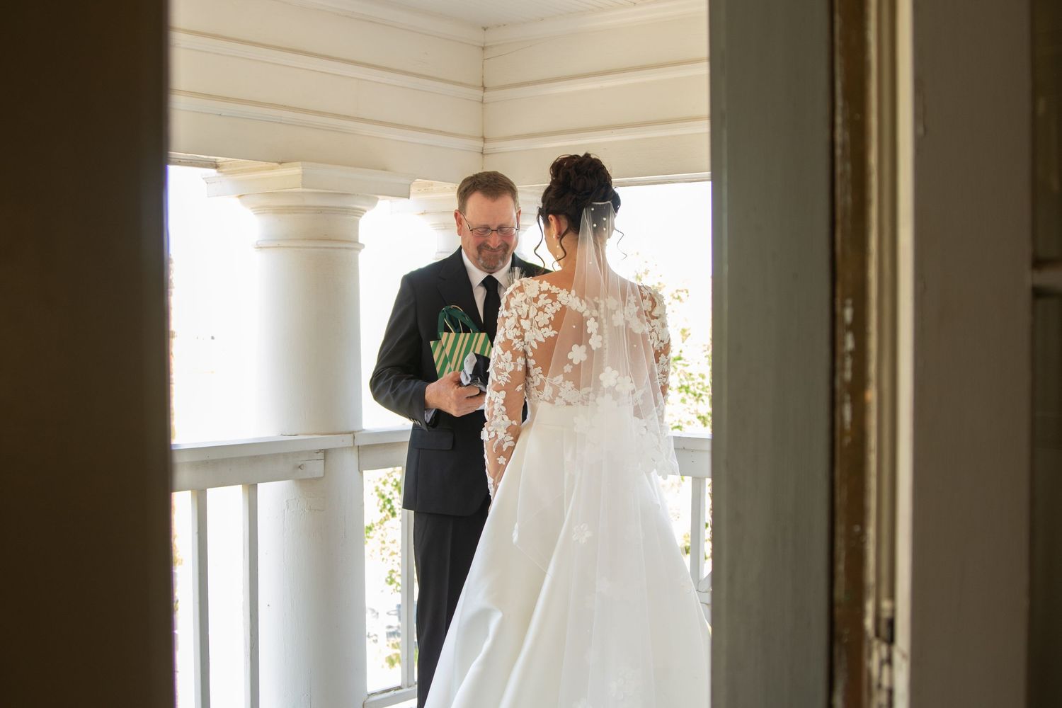 Wedding ceremony first look moment in an elegant white columned space.