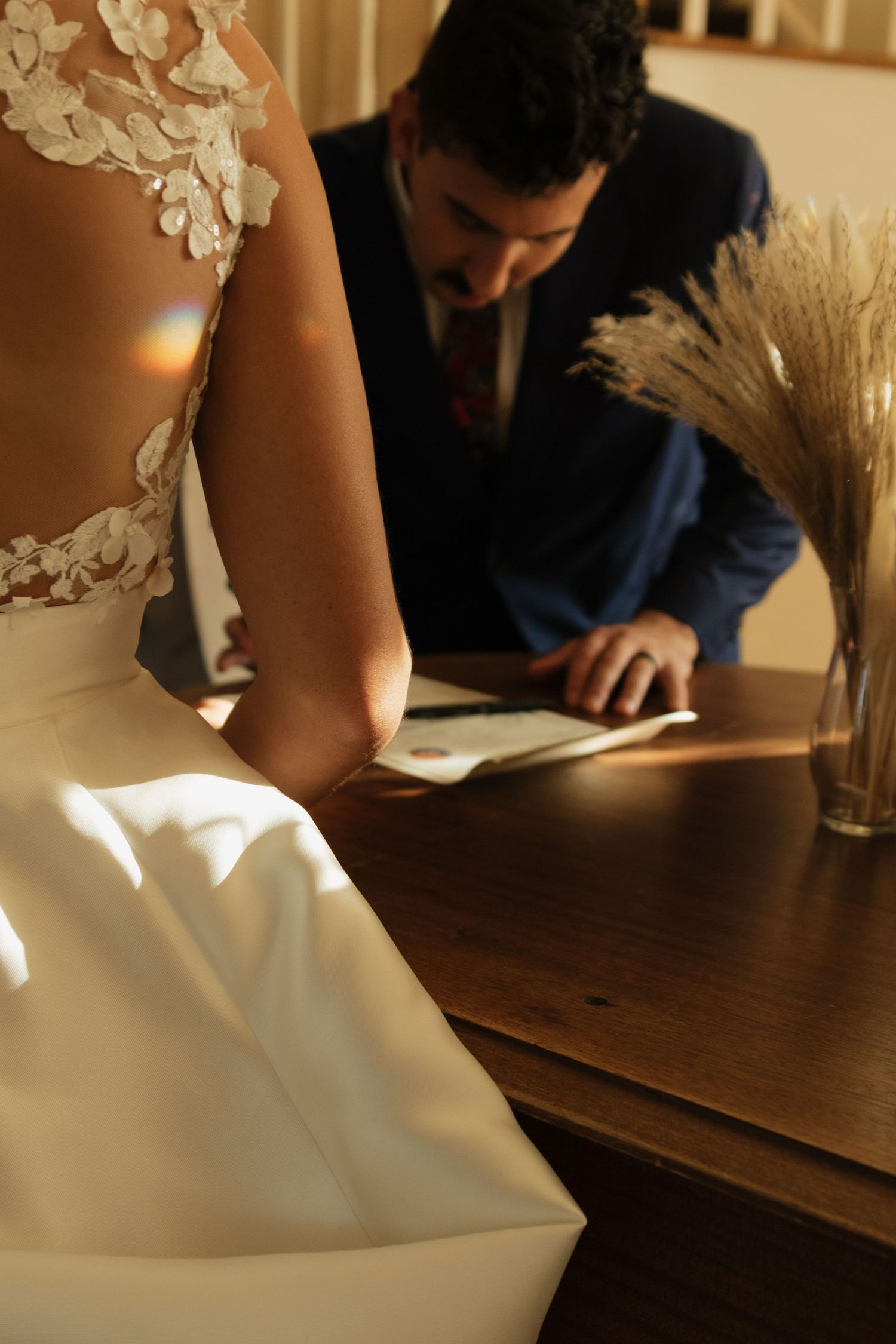 Close-up of wedding document signing on wooden table with natural light.